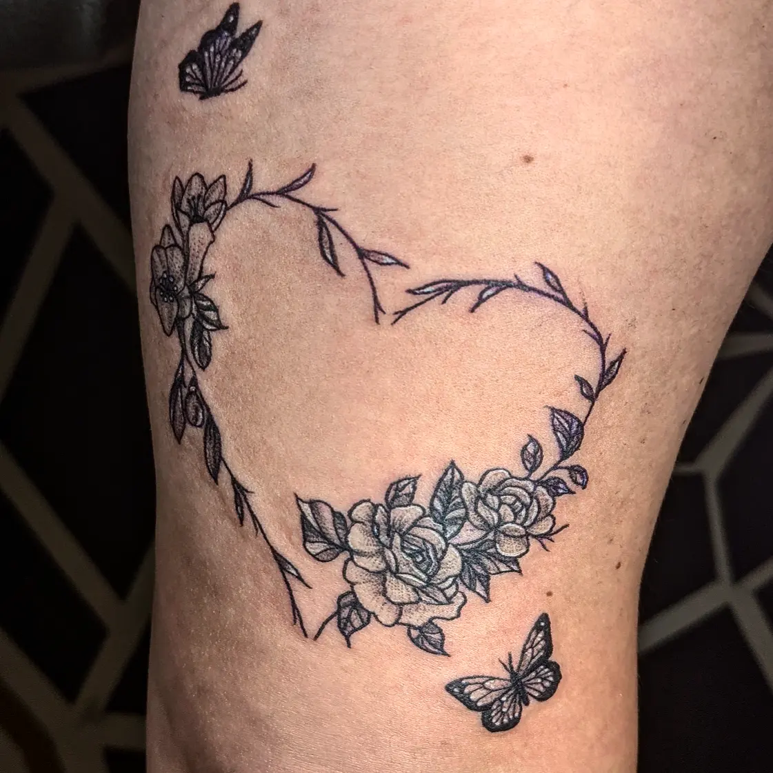 Heart with floral wreath fine line tattoo on the forearm by Aim 🤍