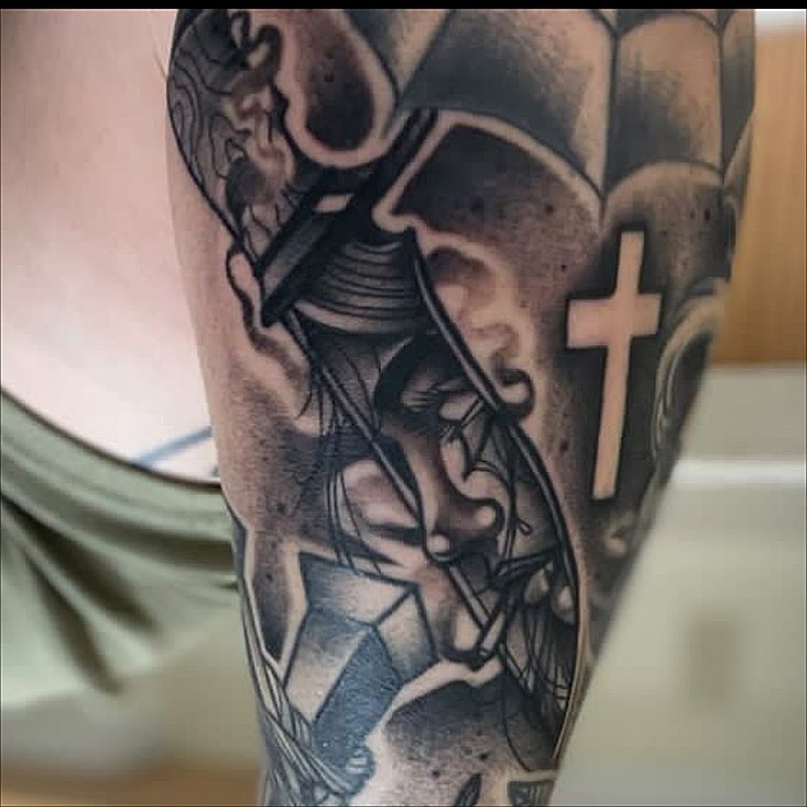 Cross and face Chicano tattoo on the forearm by Cody Wolfe