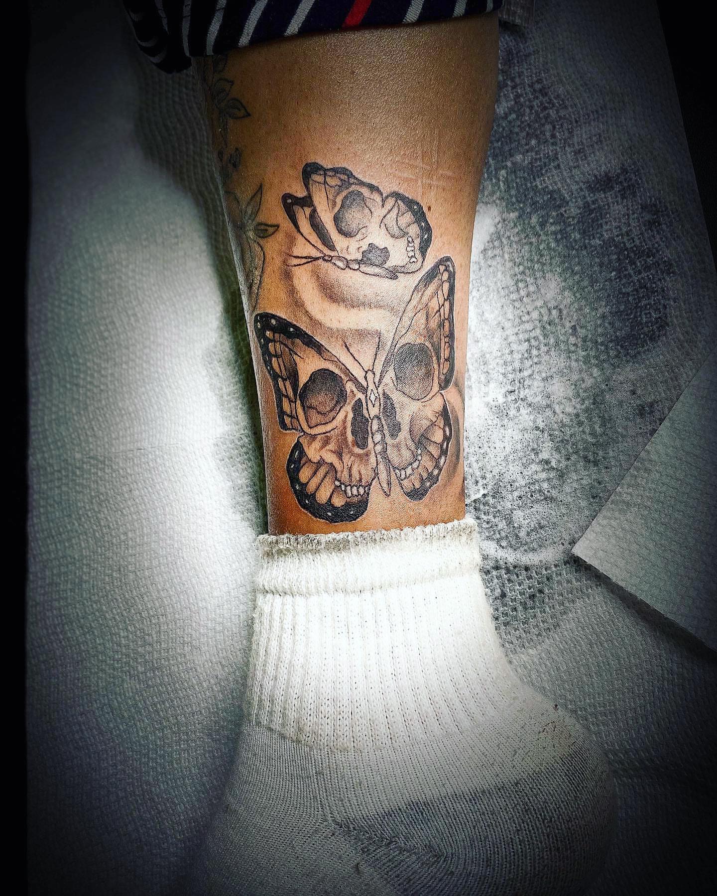 Skulls and butterfly realism tattoo on the forearm by Traveling Tattoo Artist π
