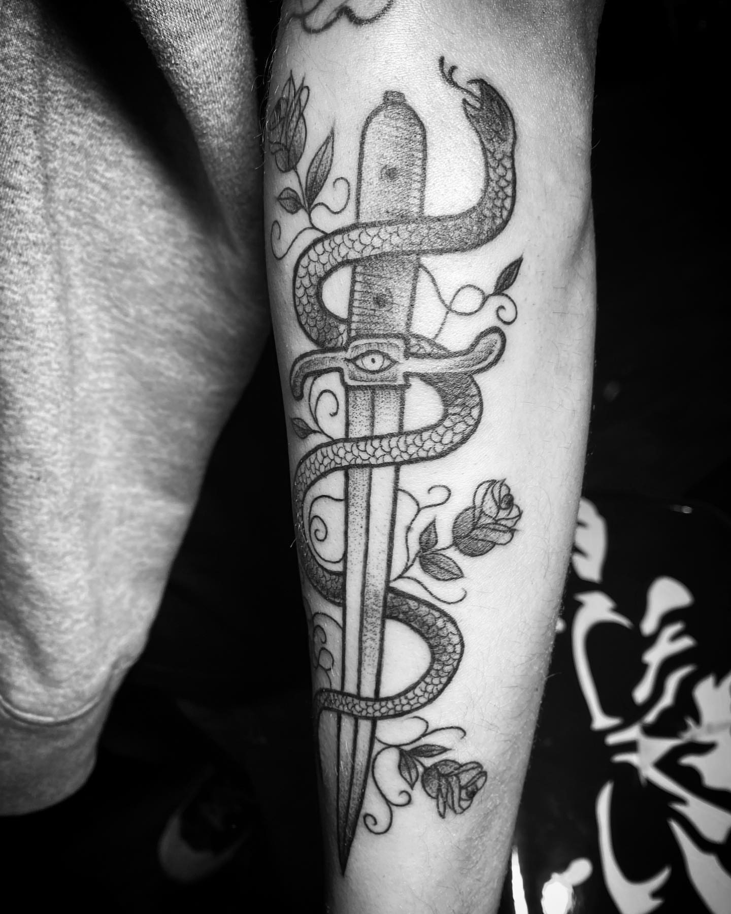 Snake and dagger black and grey tattoo on the forearm by Visionary Tattoos