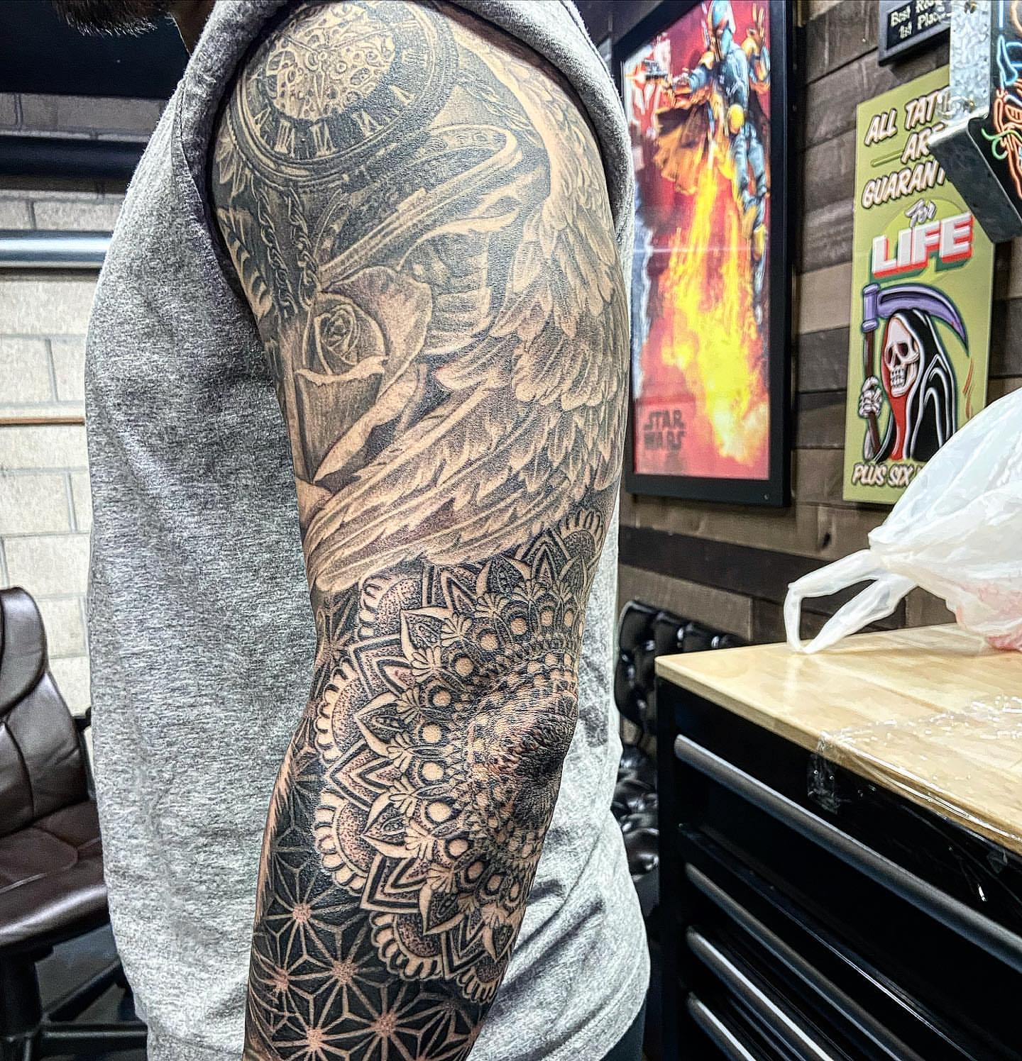Winged angel geometric tattoo on the upper arm by Creeper tattoo