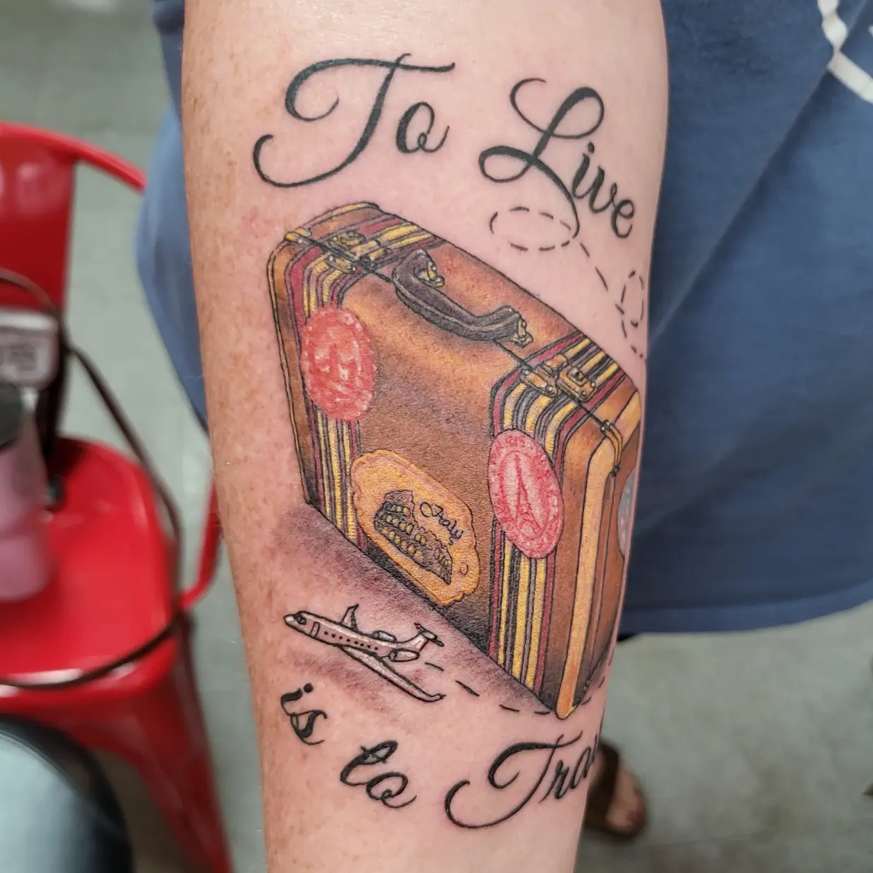 Suitcase with travel stickers realism tattoo on the forearm by Mike Stamper