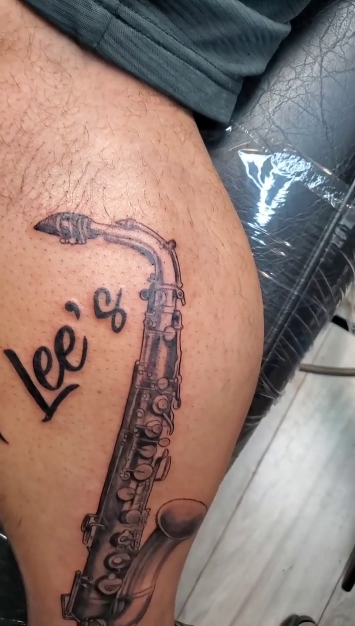 Saxophone with script realism tattoo by Chris TL Jones