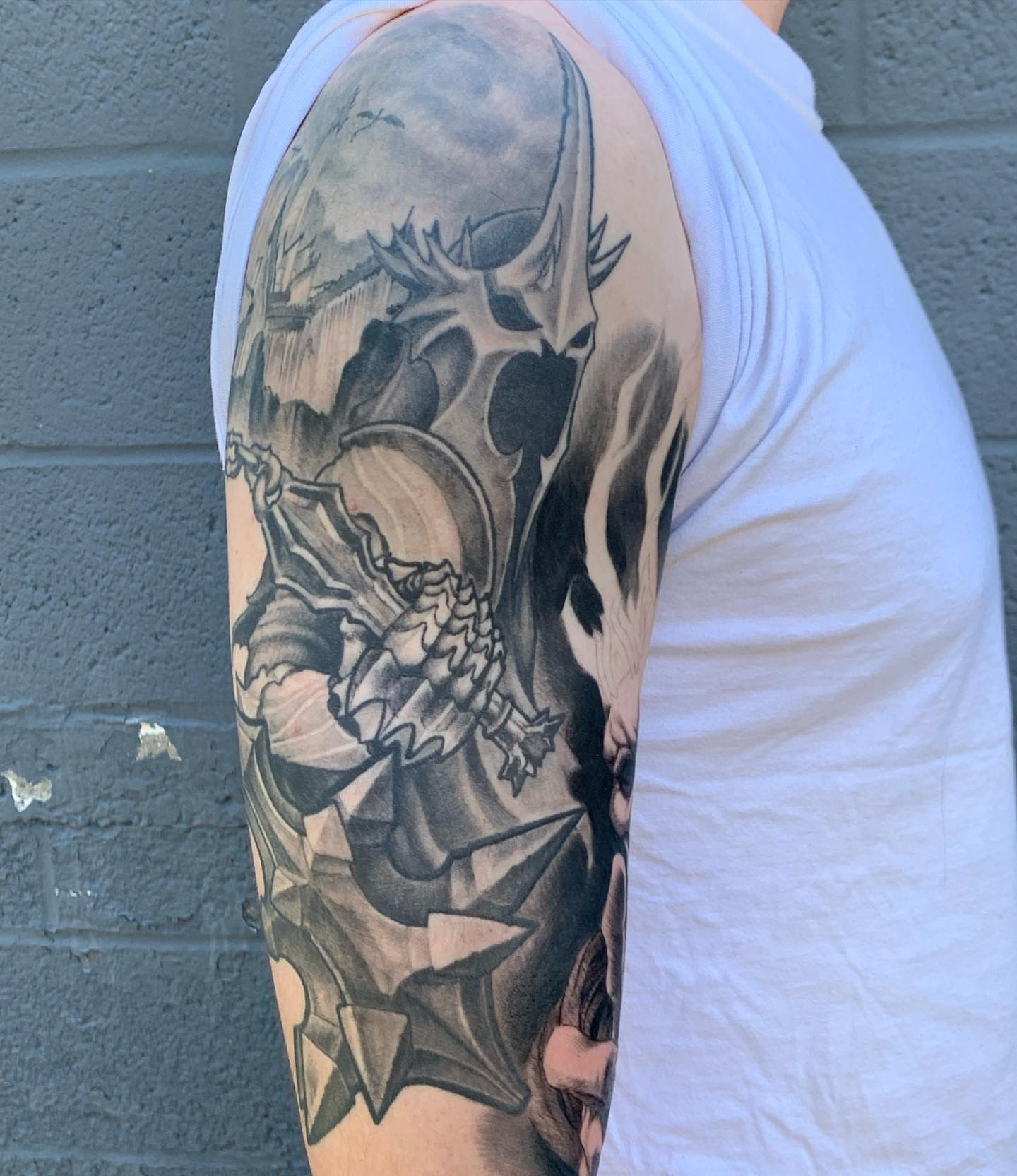Skull and wings realism tattoo on the upper arm by shane baker