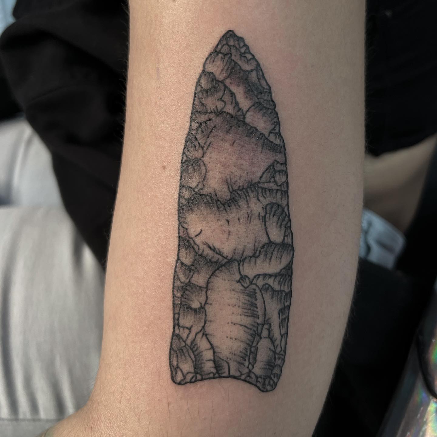 Arrowhead black and grey tattoo on the forearm by Syd Cheyenne