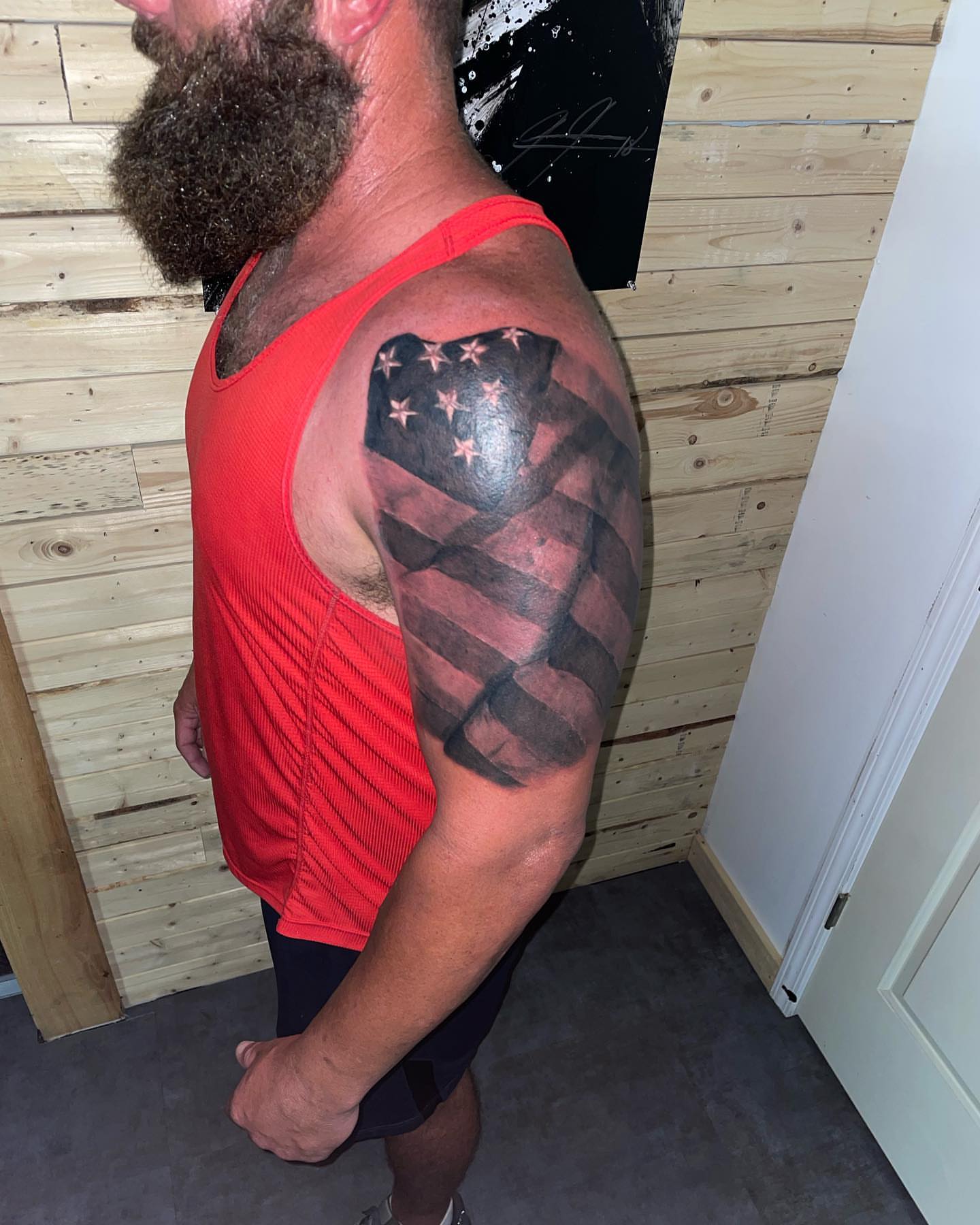 American flag black and grey tattoo on the upper arm by Zach Ashton