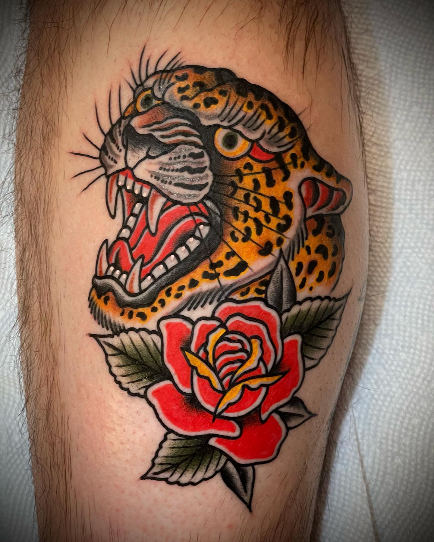 Jaguar and rose American traditional tattoo on the forearm by Alex Muniz
