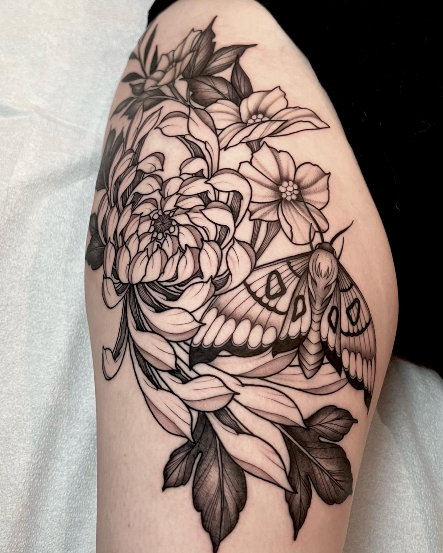 Flower moth realism tattoo on the thigh by Chelsea Darling
