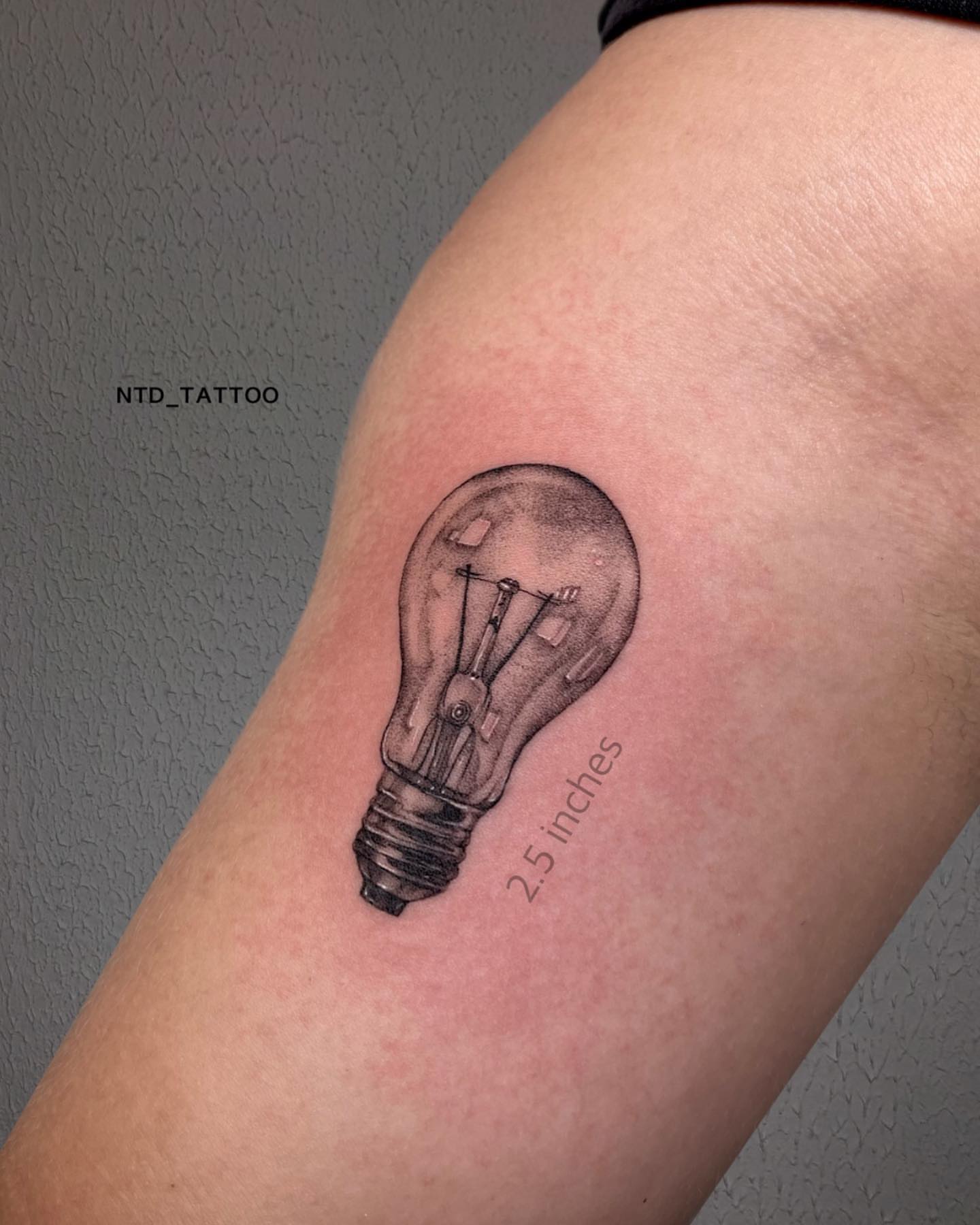 Light bulb black and grey tattoo on the forearm by Tetiana Maxon