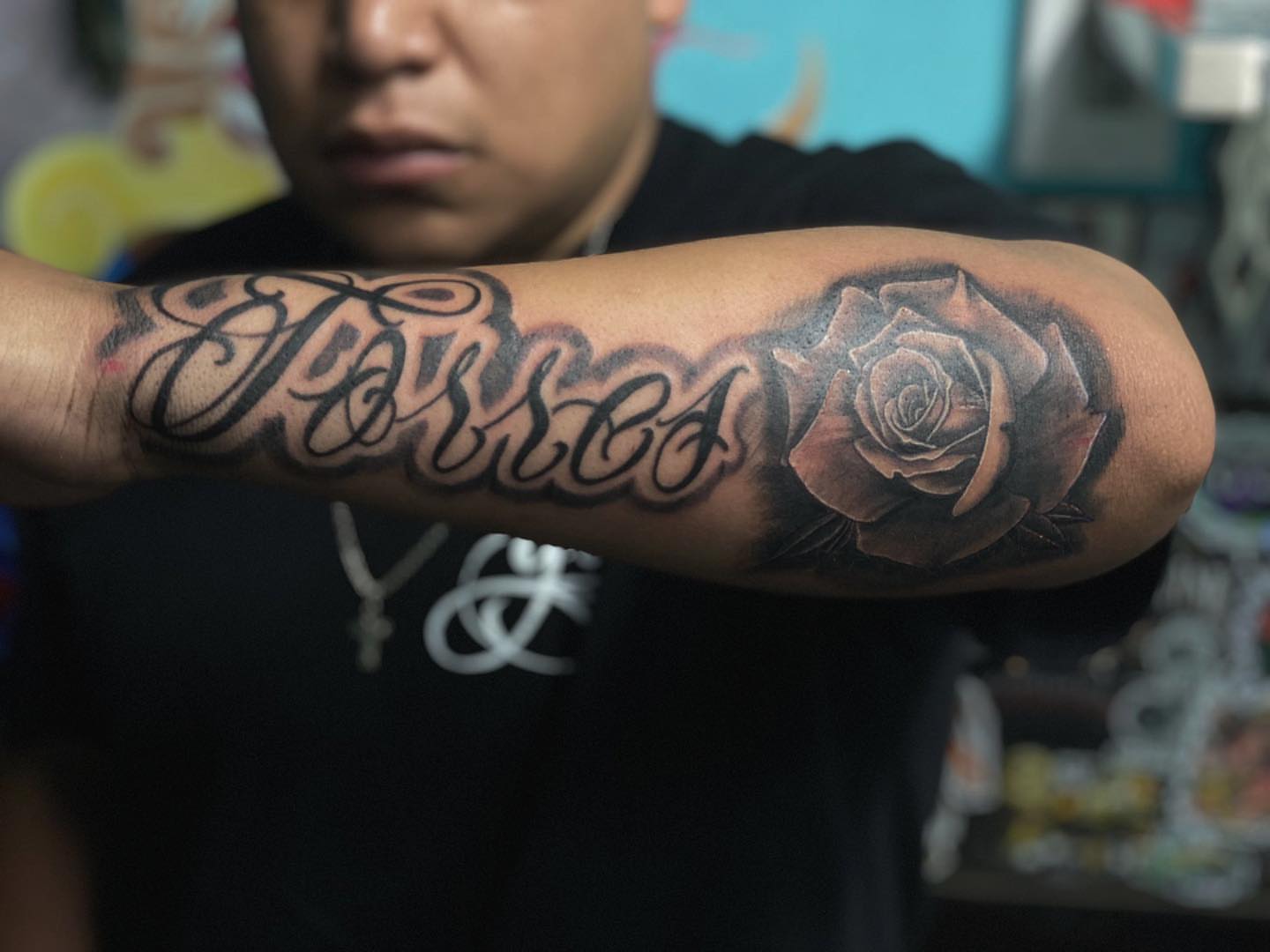Rose and cursive script realism tattoo on the forearm by Alberto Ramirez