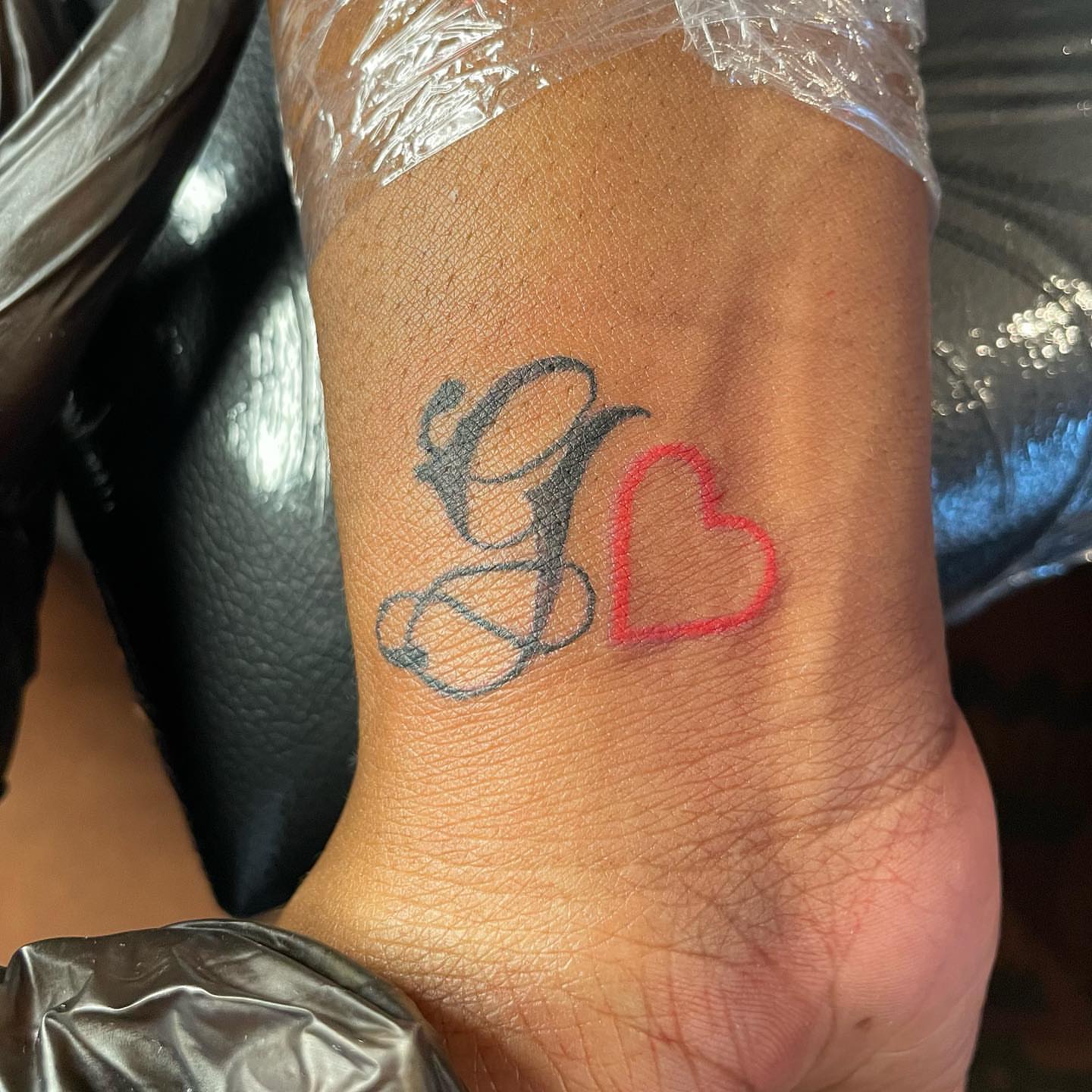 Initial and heart lettering script tattoo on the forearm by Lea-yae’