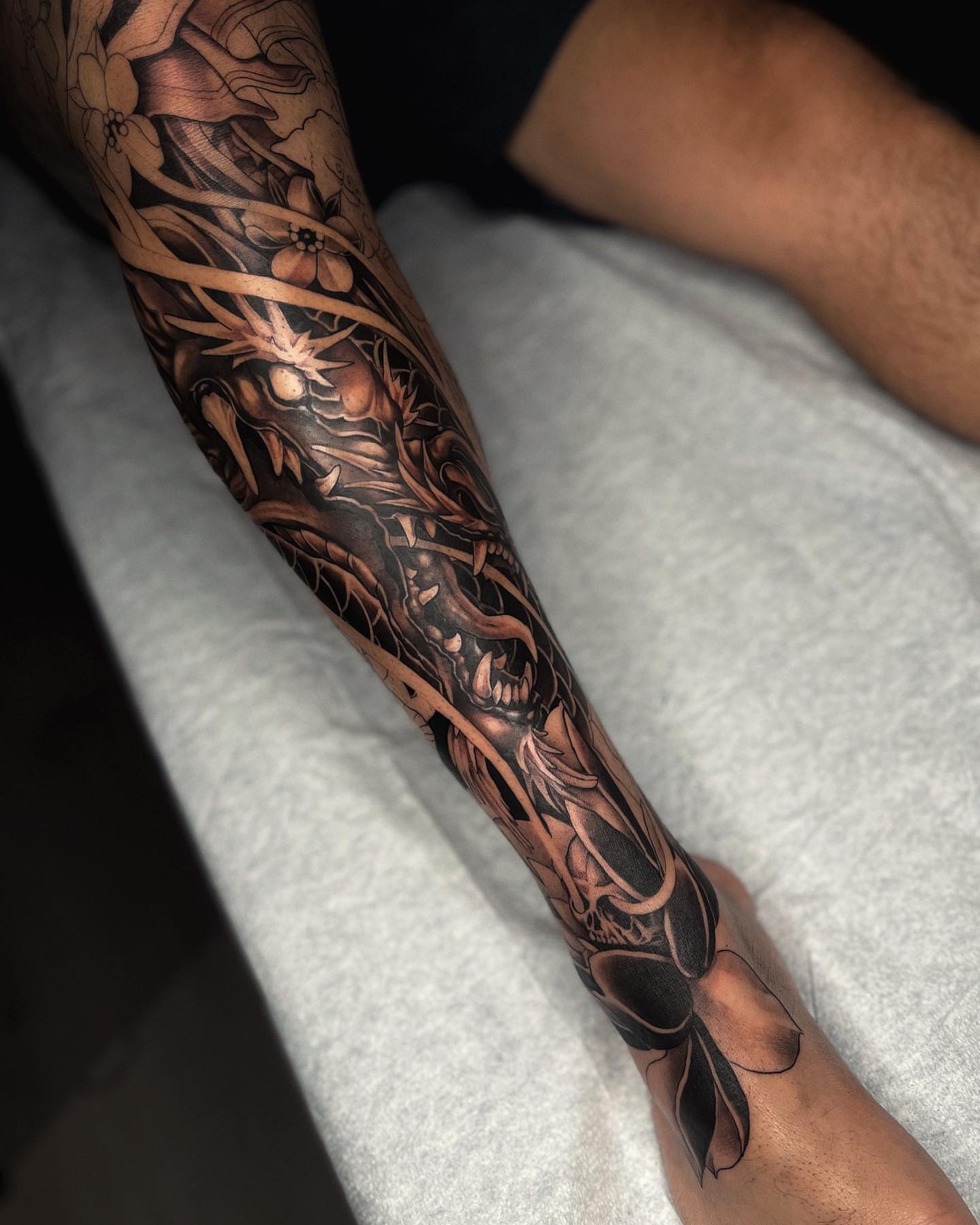 Floral and skeletal motifs dark realism tattoo on the forearm by Jennal Wang
