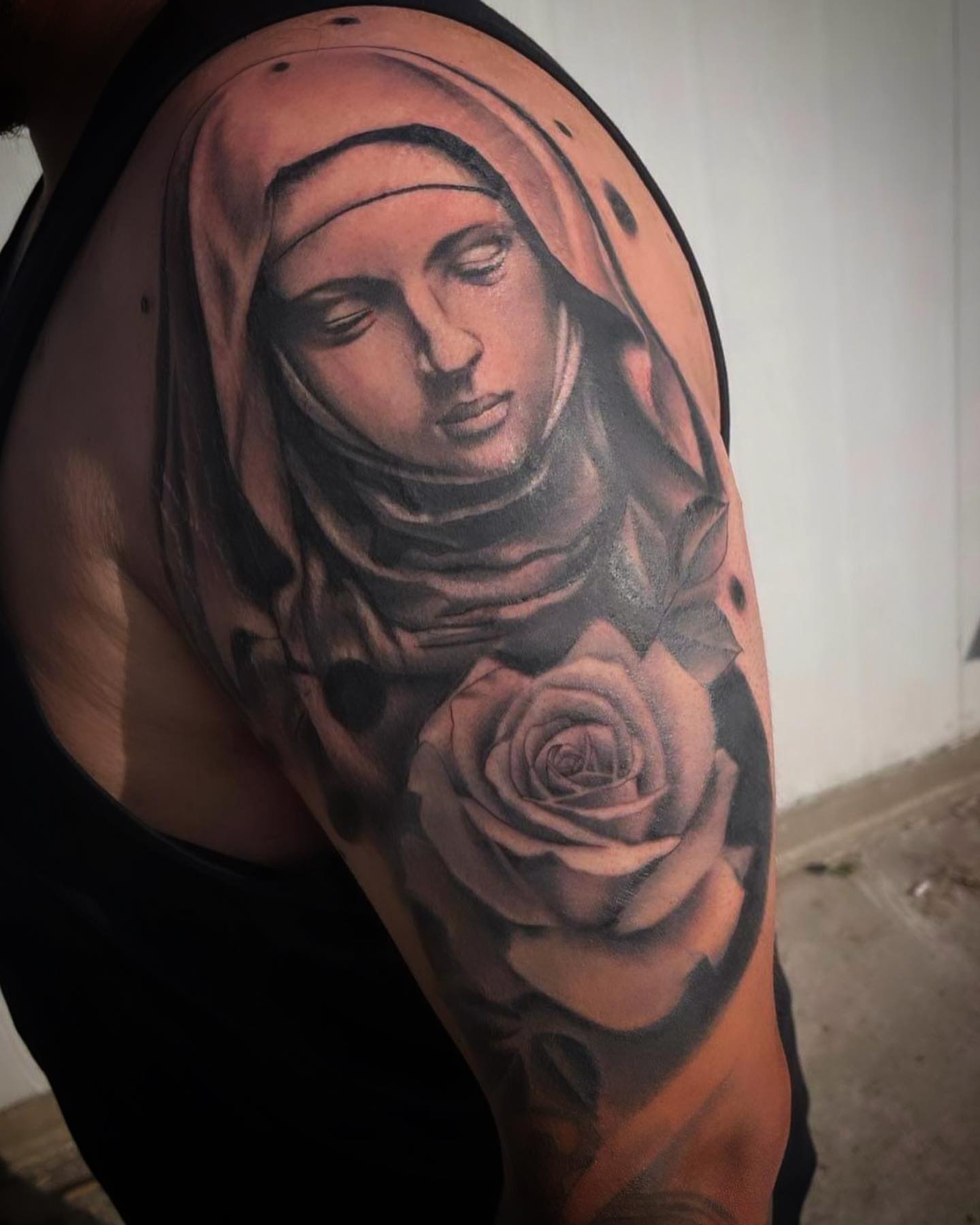 Religious figure with rose realism tattoo on the shoulder by @tattoos_by_elijah