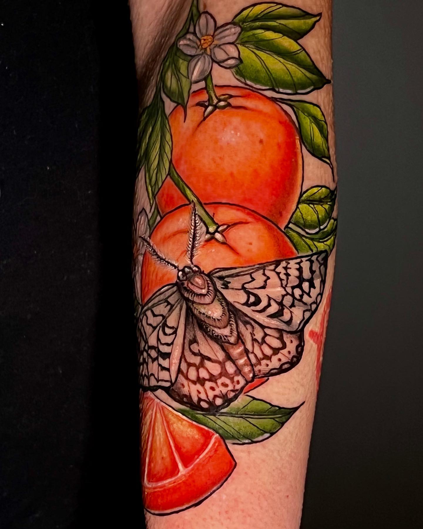 Orange moth American traditional tattoo on the forearm by Josh Green