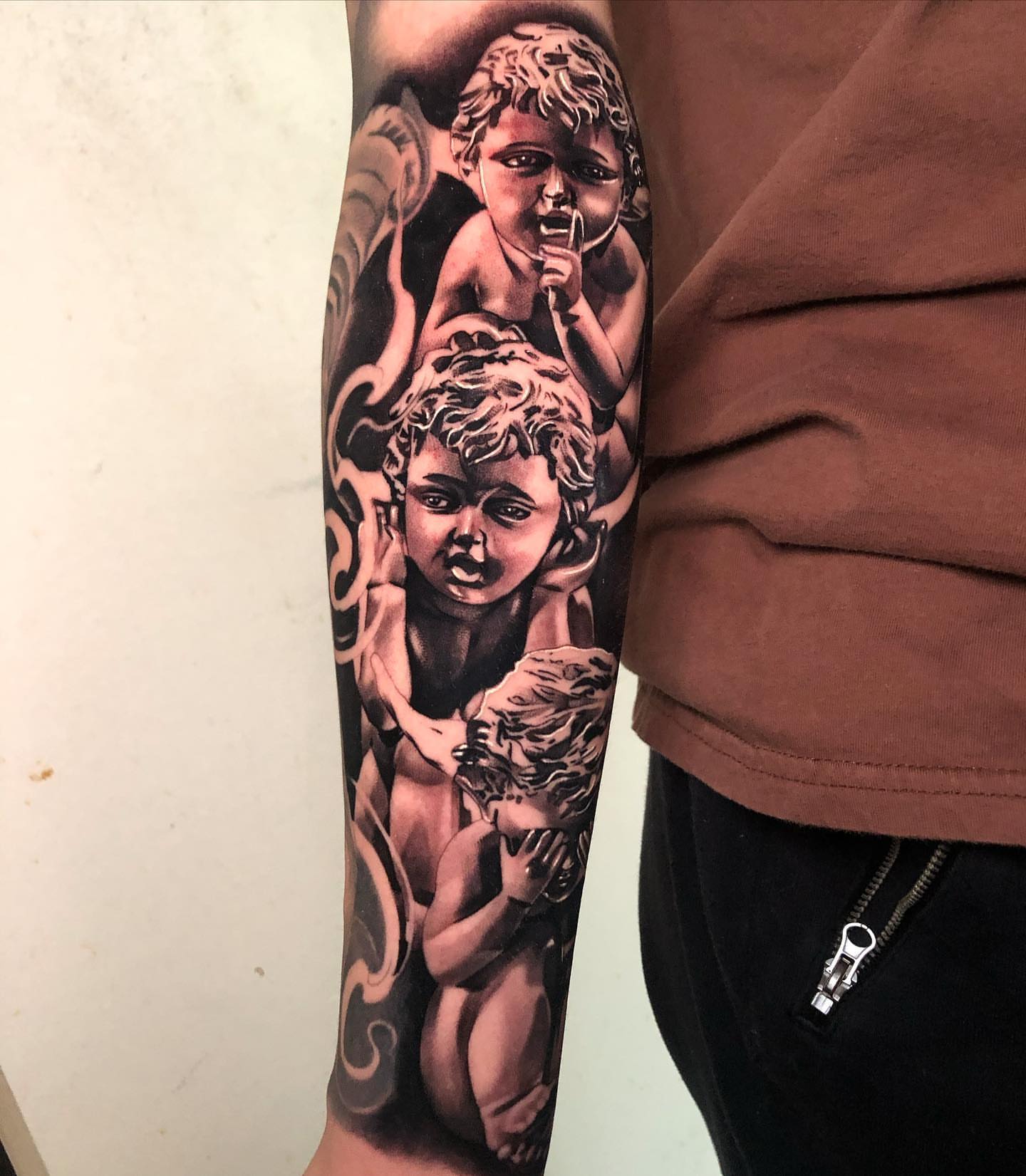 Cherubs black and grey tattoo on the forearm by Michael Martinez