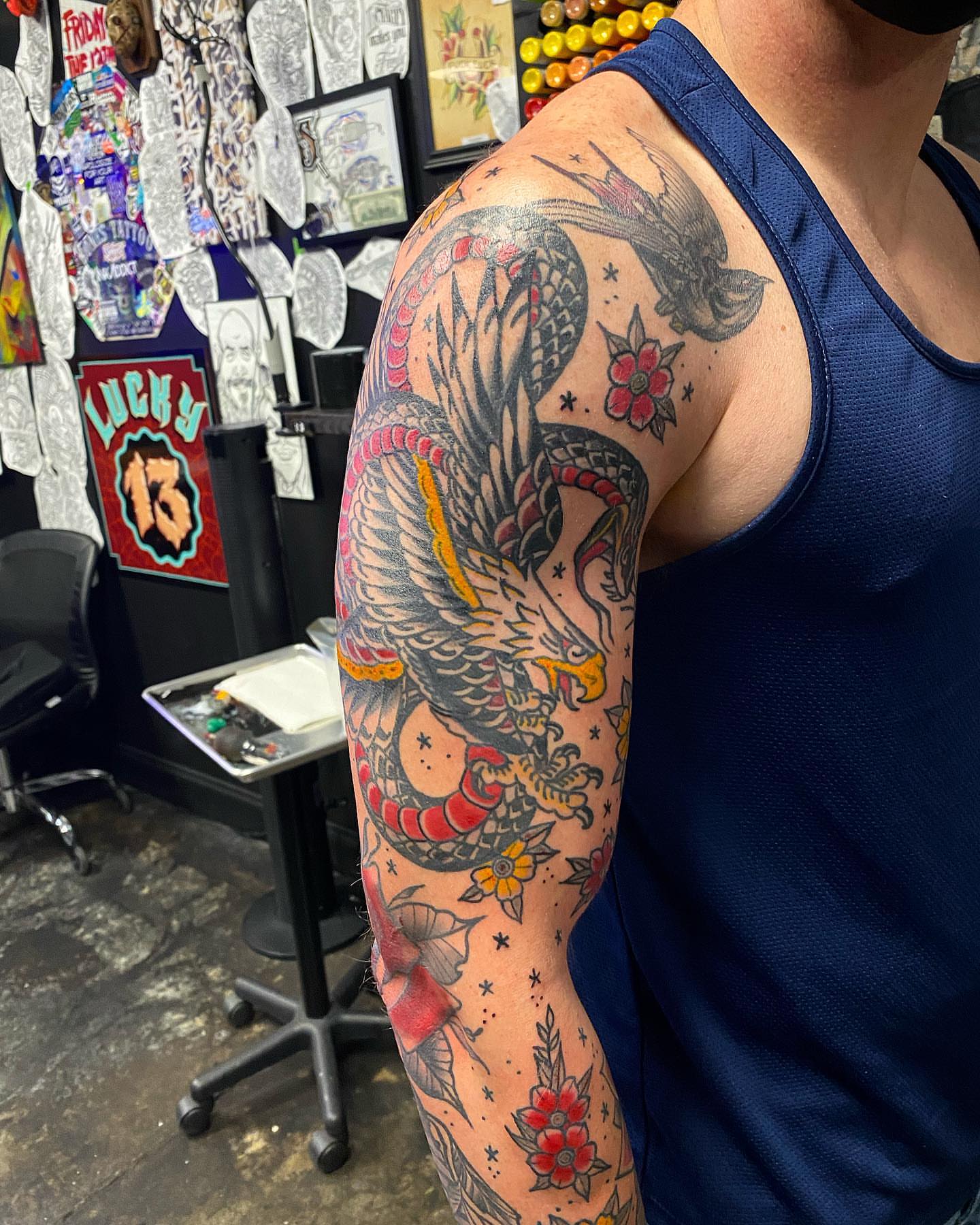 Dragon and flowers American traditional tattoo on the upper arm by Josh St.germain