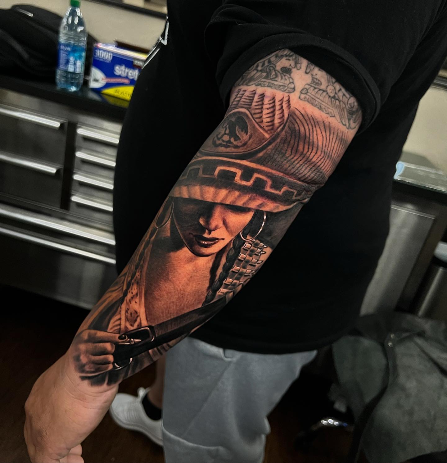 Woman with headdress realism tattoo on the forearm by Angel Lizarraga