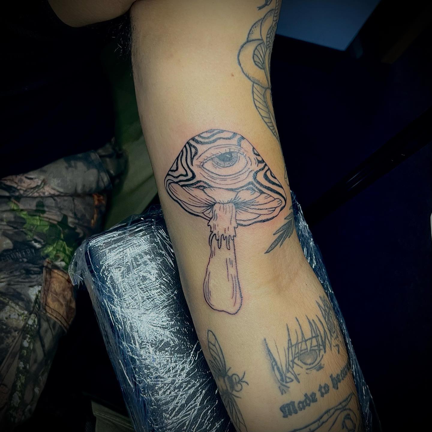 Mushroom with eye black and grey tattoo on the forearm by @tattsbyleek