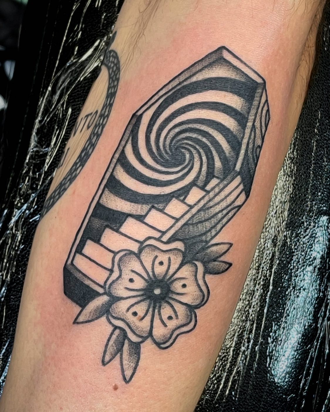 Hypnotic spiral and flower geometric tattoo on the forearm by Dave Shurman