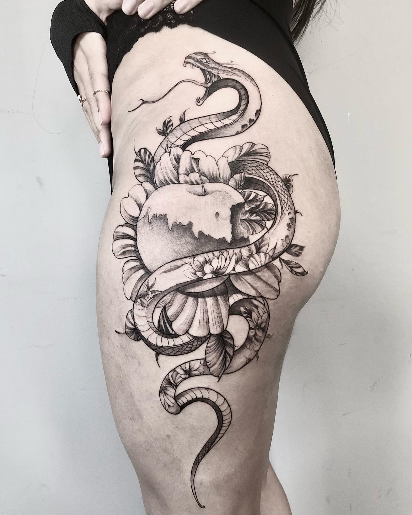 Snake and apple realism tattoo on the thigh by Shihao zhao