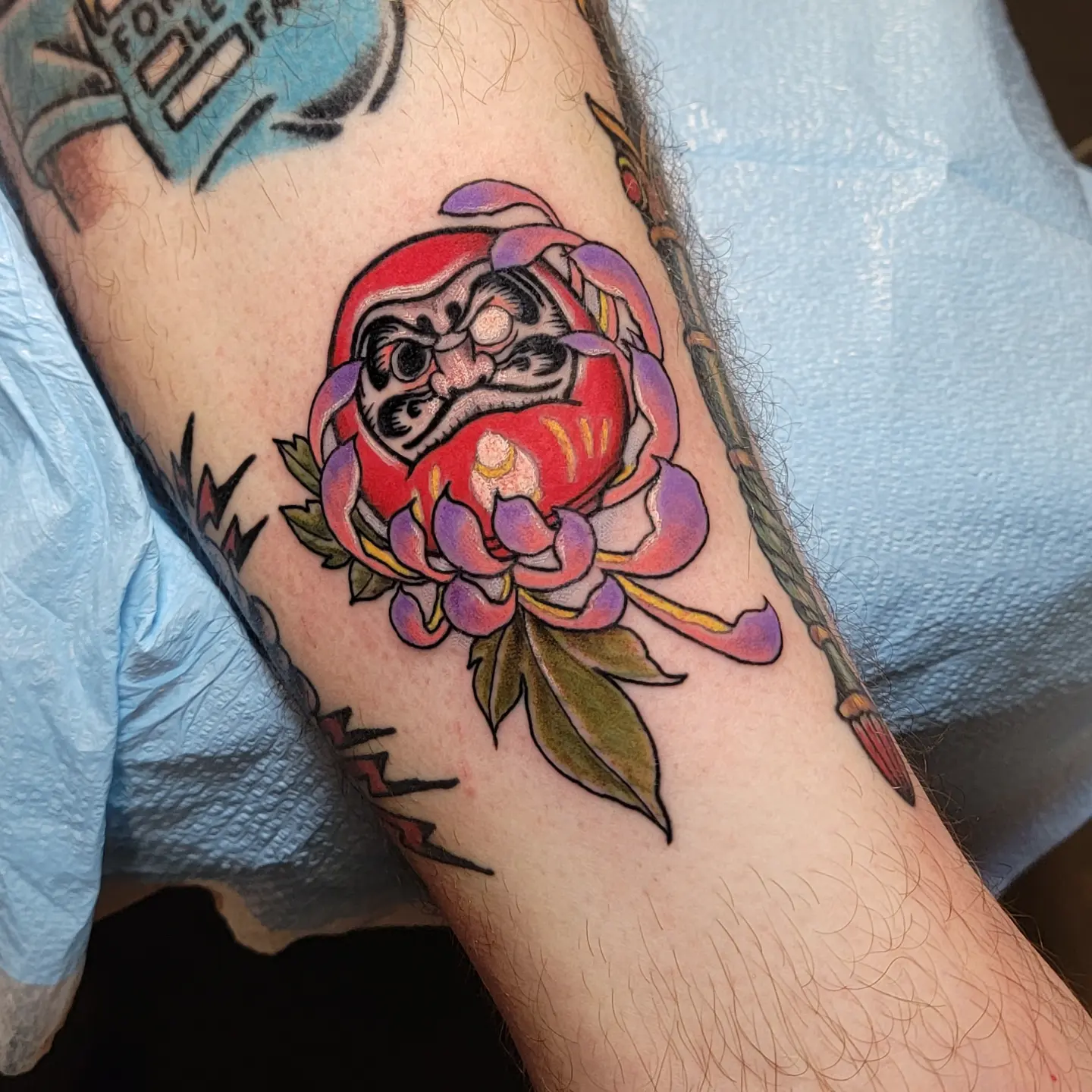 Demon doll and flower American traditional tattoo on the forearm by ๐๏ธ, Ashland, Virginia