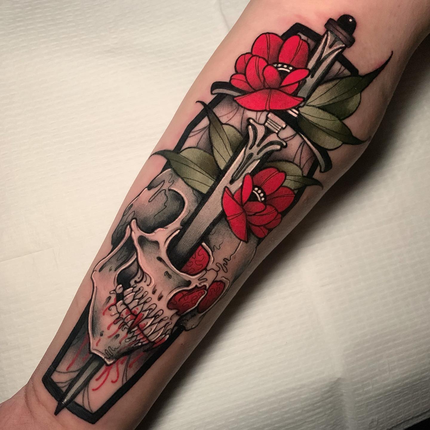 Skull and flowers American traditional tattoo on the forearm by gillian marie
