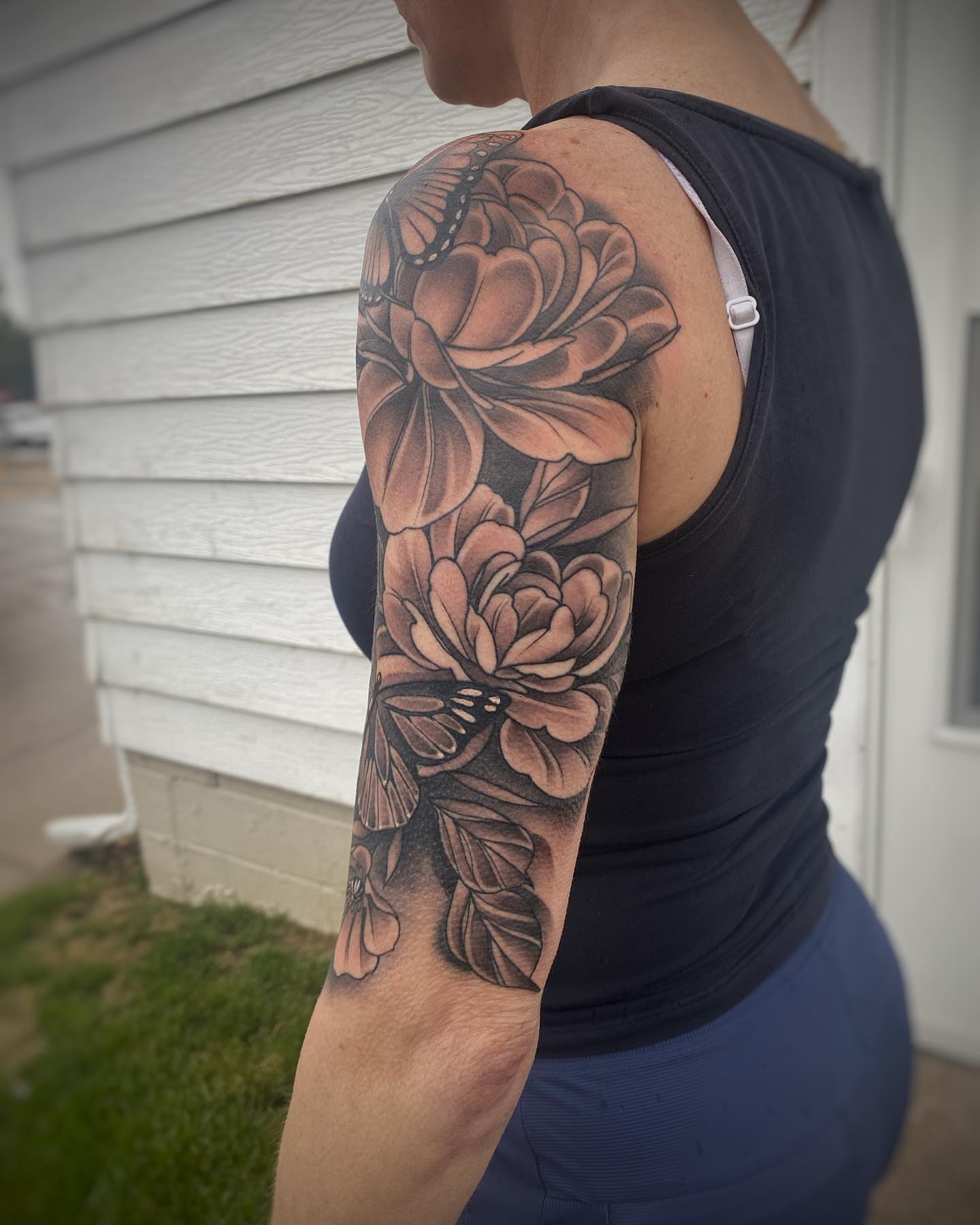 Flowers and butterfly realism tattoo on the upper arm by Derek Hutchison, Des Moines, Iowa