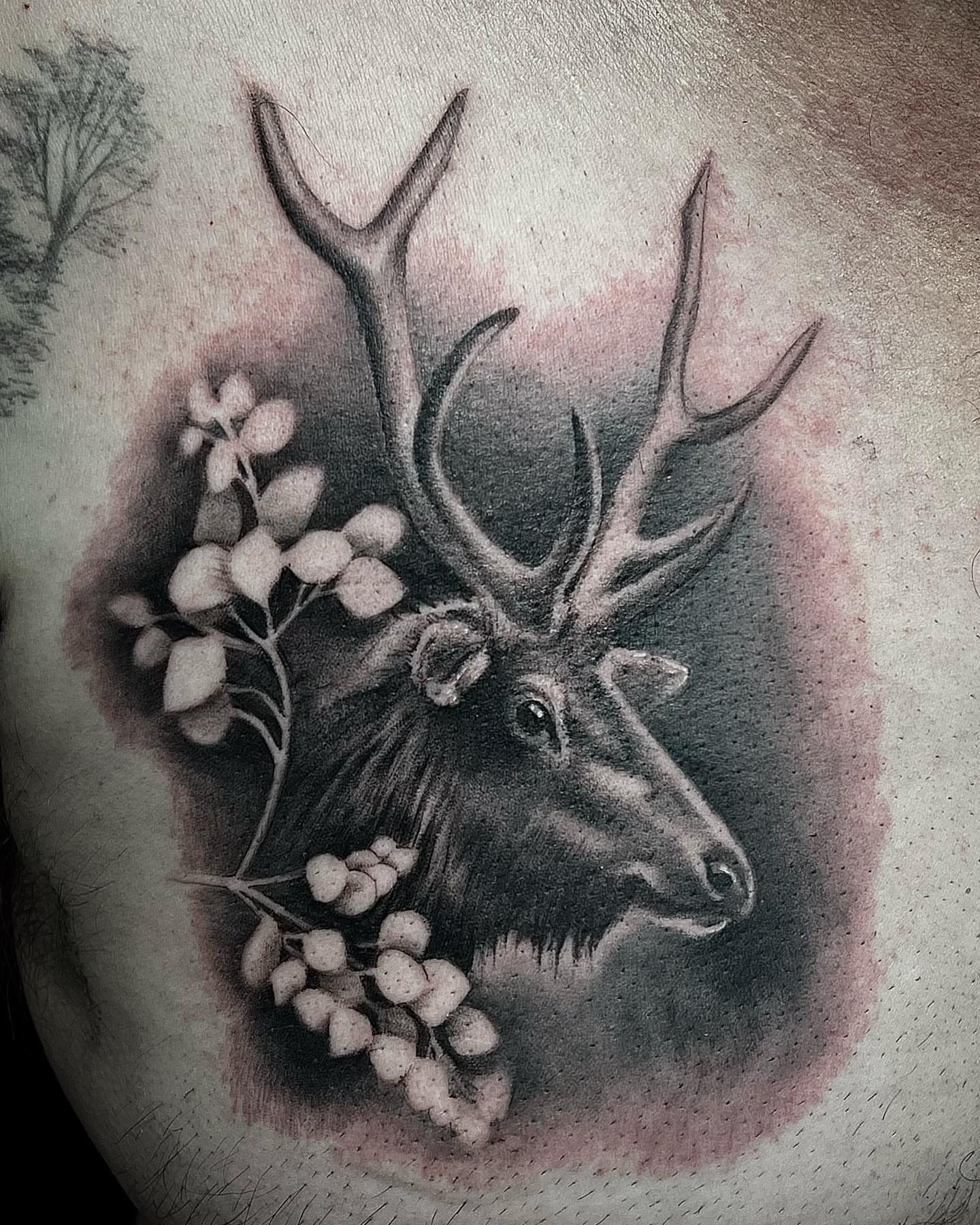 Deer head with berries realism tattoo on the chest by Madison Ast Tattoo