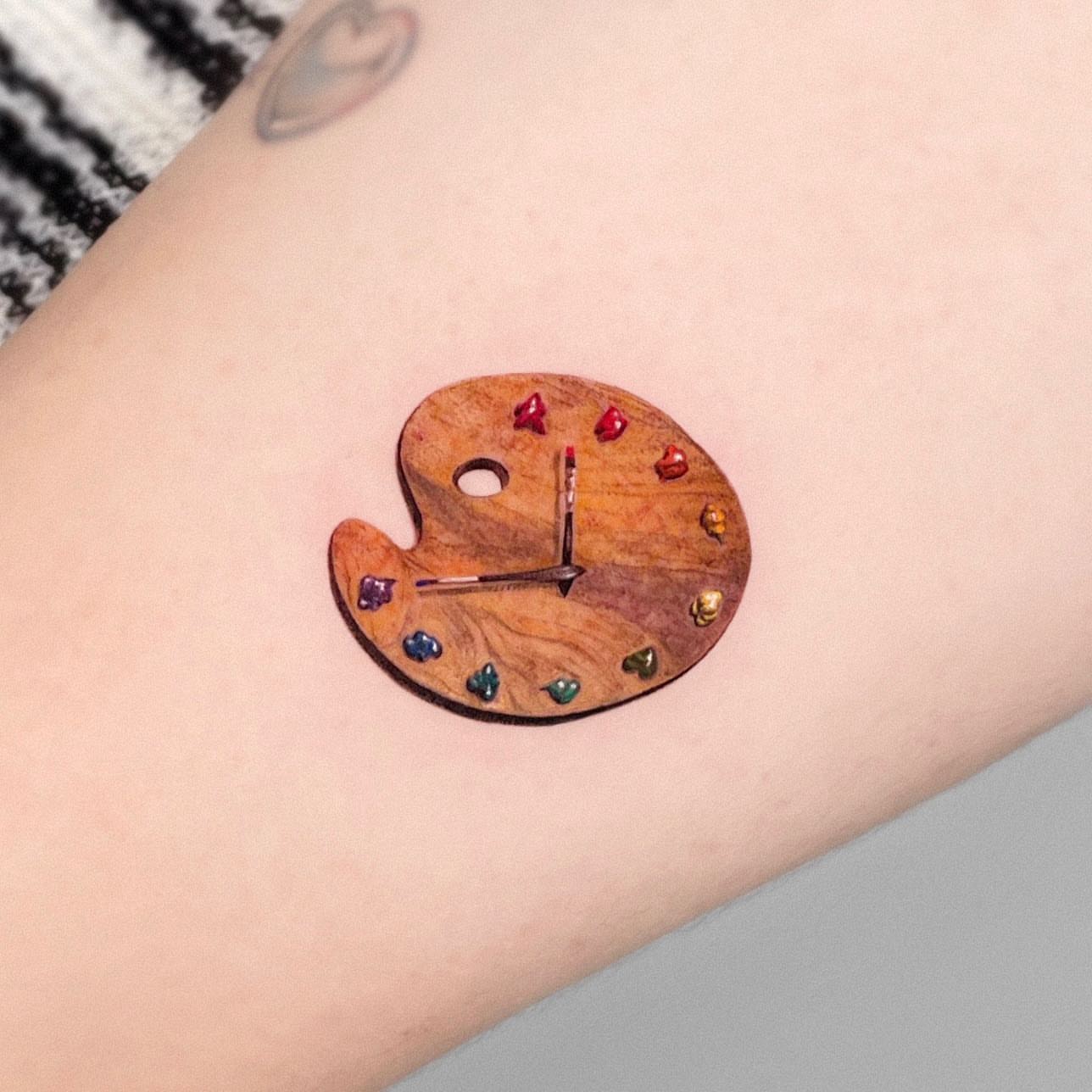 Artist palette clock realism tattoo on the forearm by Yeye