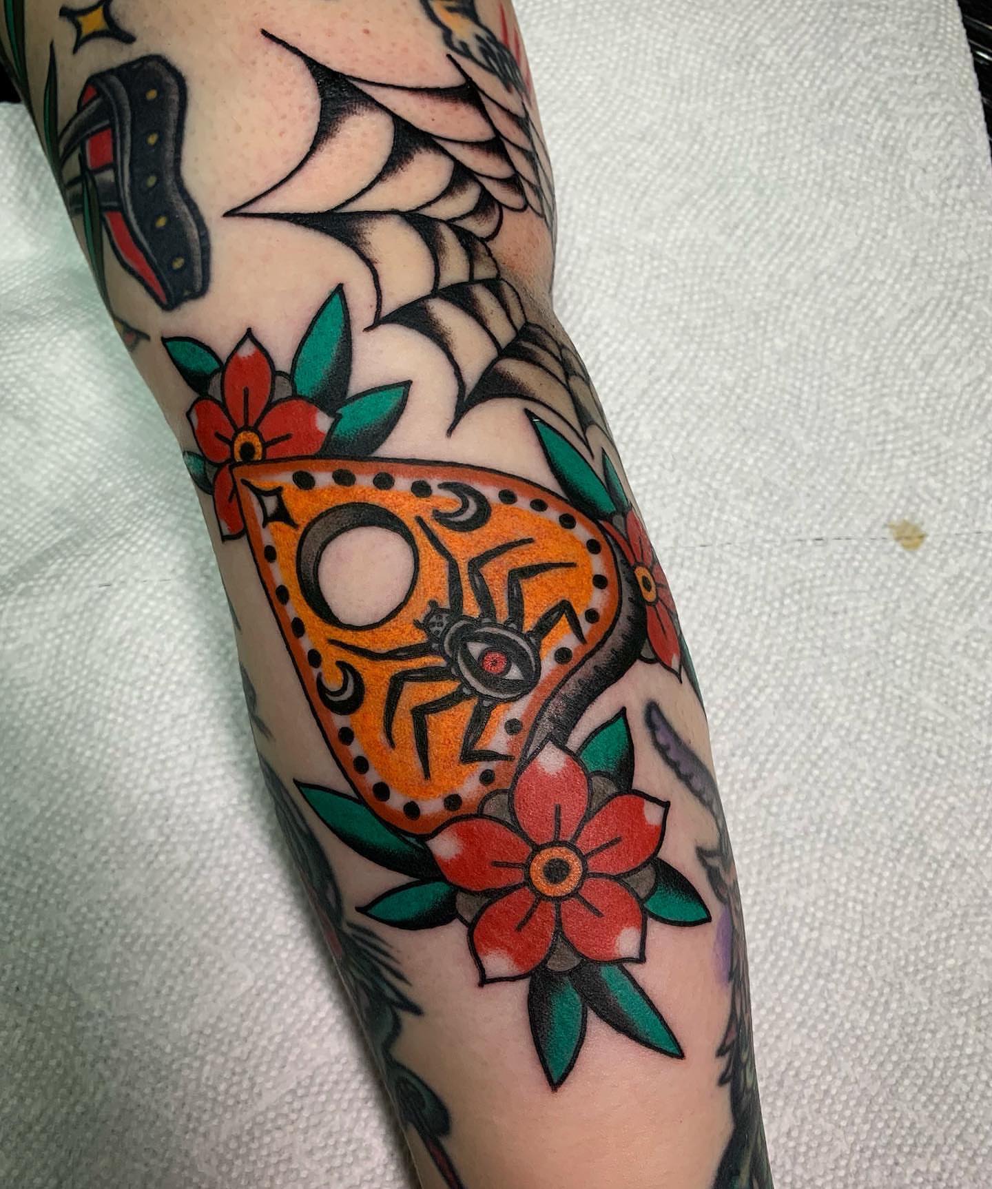 Butterfly and flowers American traditional tattoo on the forearm by Ethan Bennett