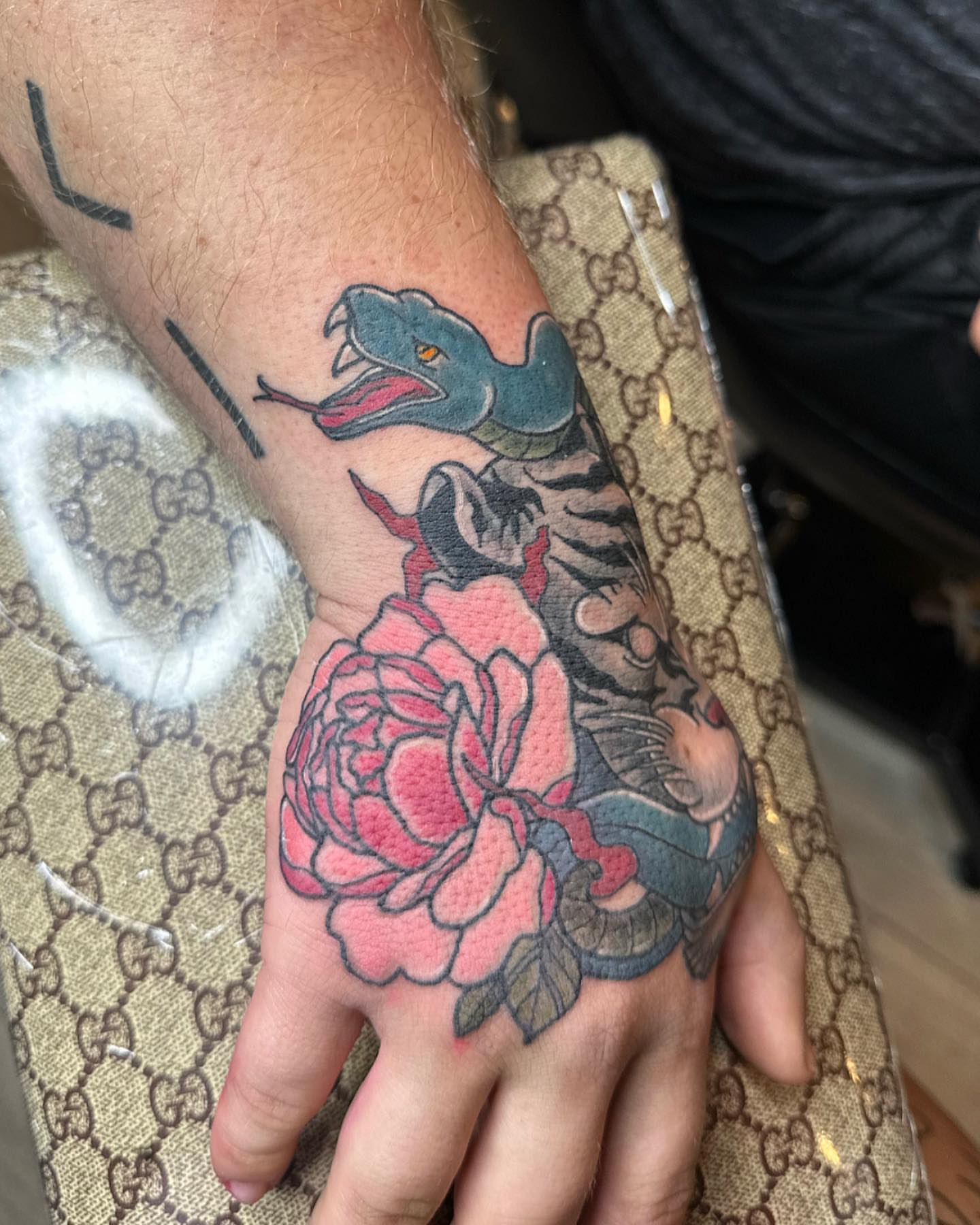 Snake and peony American traditional tattoo on the hand by Diana Kunz