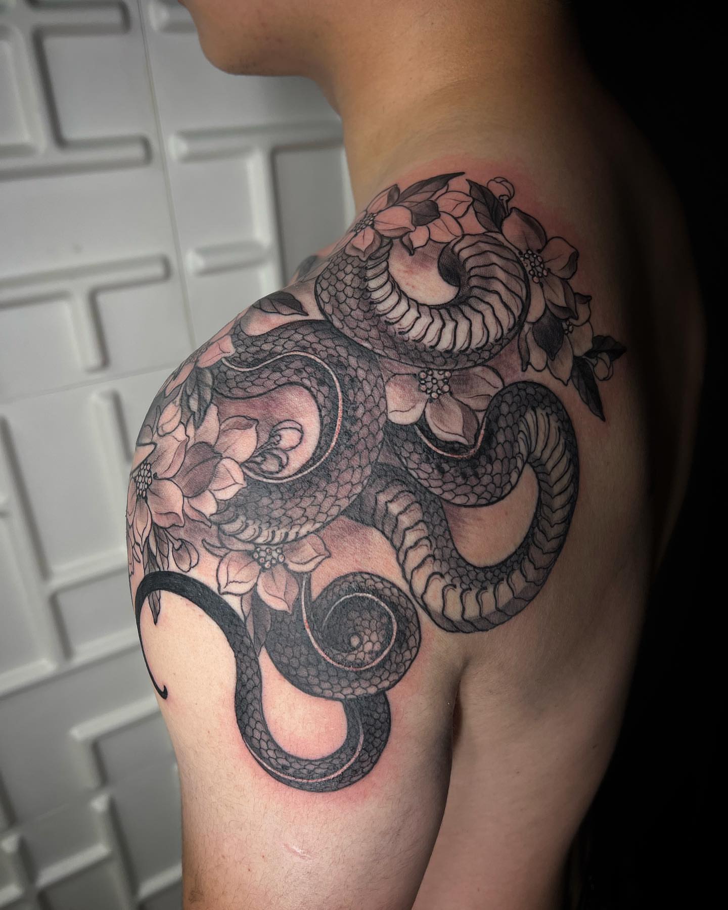Snake and flowers realism tattoo on the shoulder by Vinny Holistic Ink