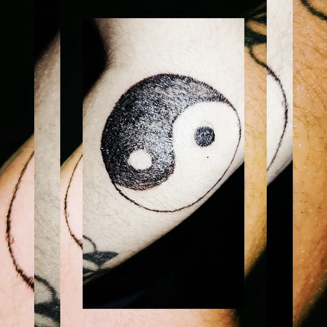 Yin yang symbol black and grey tattoo on the forearm by Tatuadora & Piercer