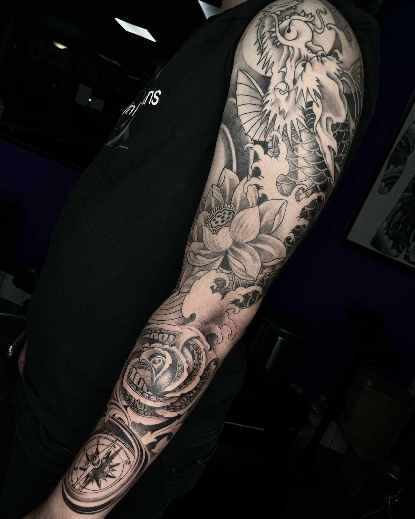Lotus flower and dragon realism tattoo on the forearm by Tam Nguyen