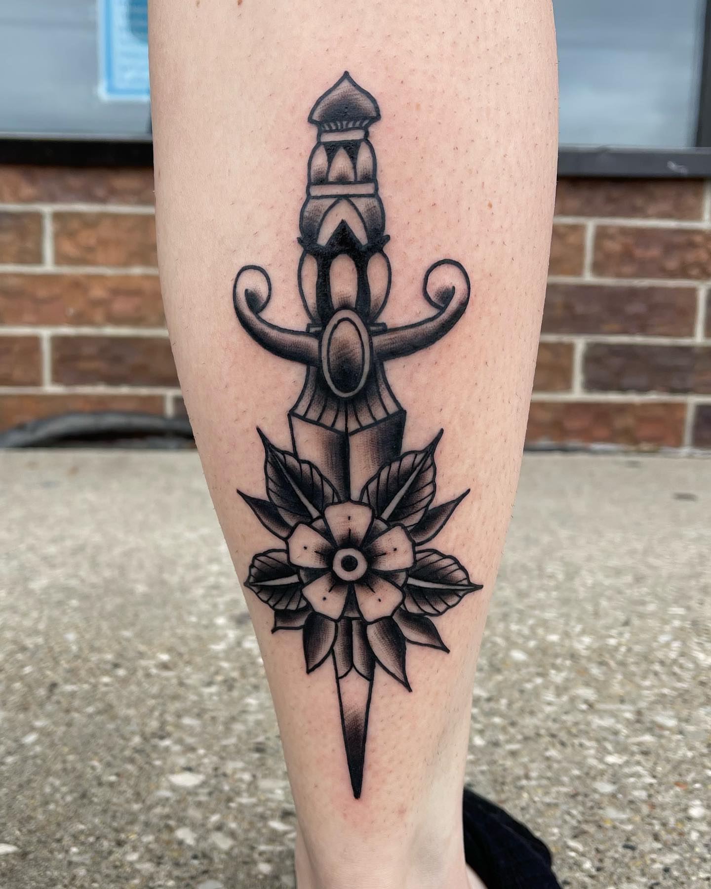 Sword and flower black and grey tattoo on the forearm by Zach Eden