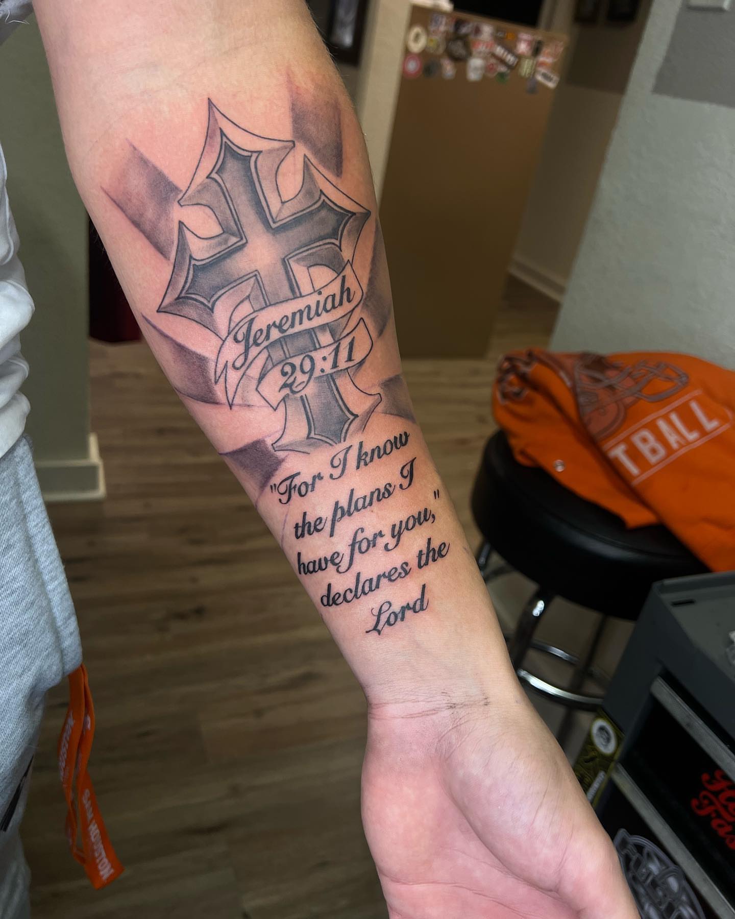 Cross with scripture black and grey tattoo on the forearm by Daphne Landry