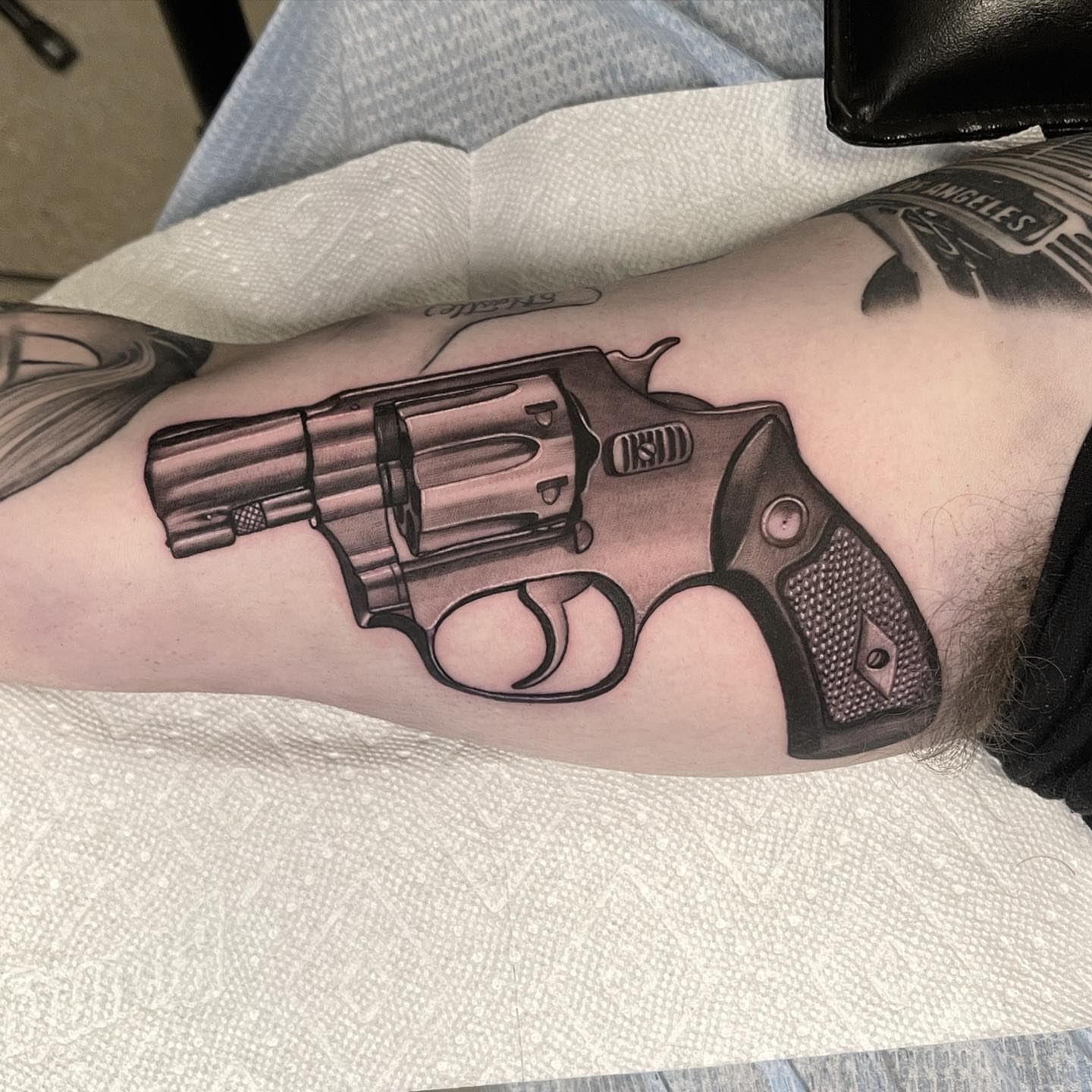 Revolver black and grey tattoo on the forearm by Jake Fujimura