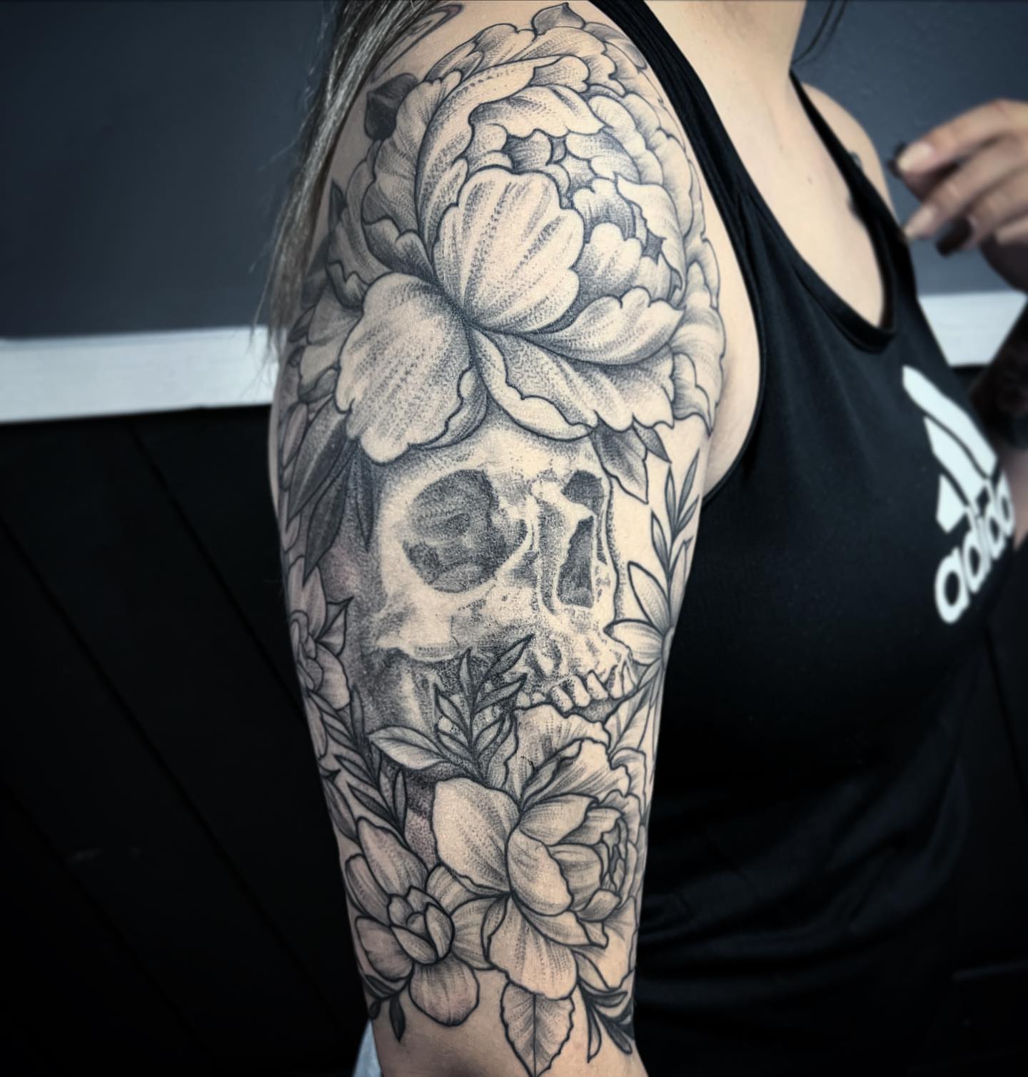 Skull and flowers realism tattoo on the upper arm by TyEsha Reels