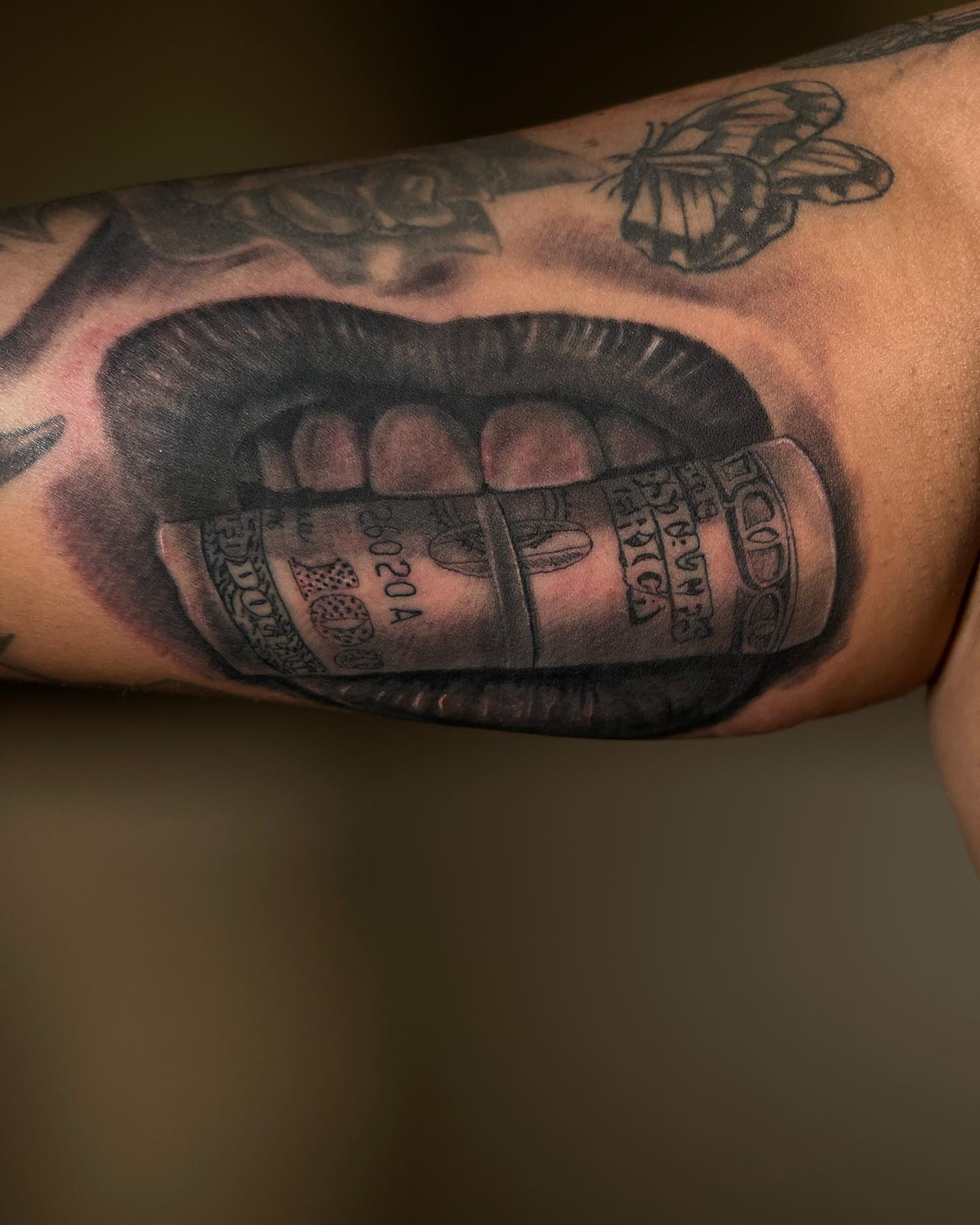 Money in mouth black and grey tattoo on the forearm by David Mariscal