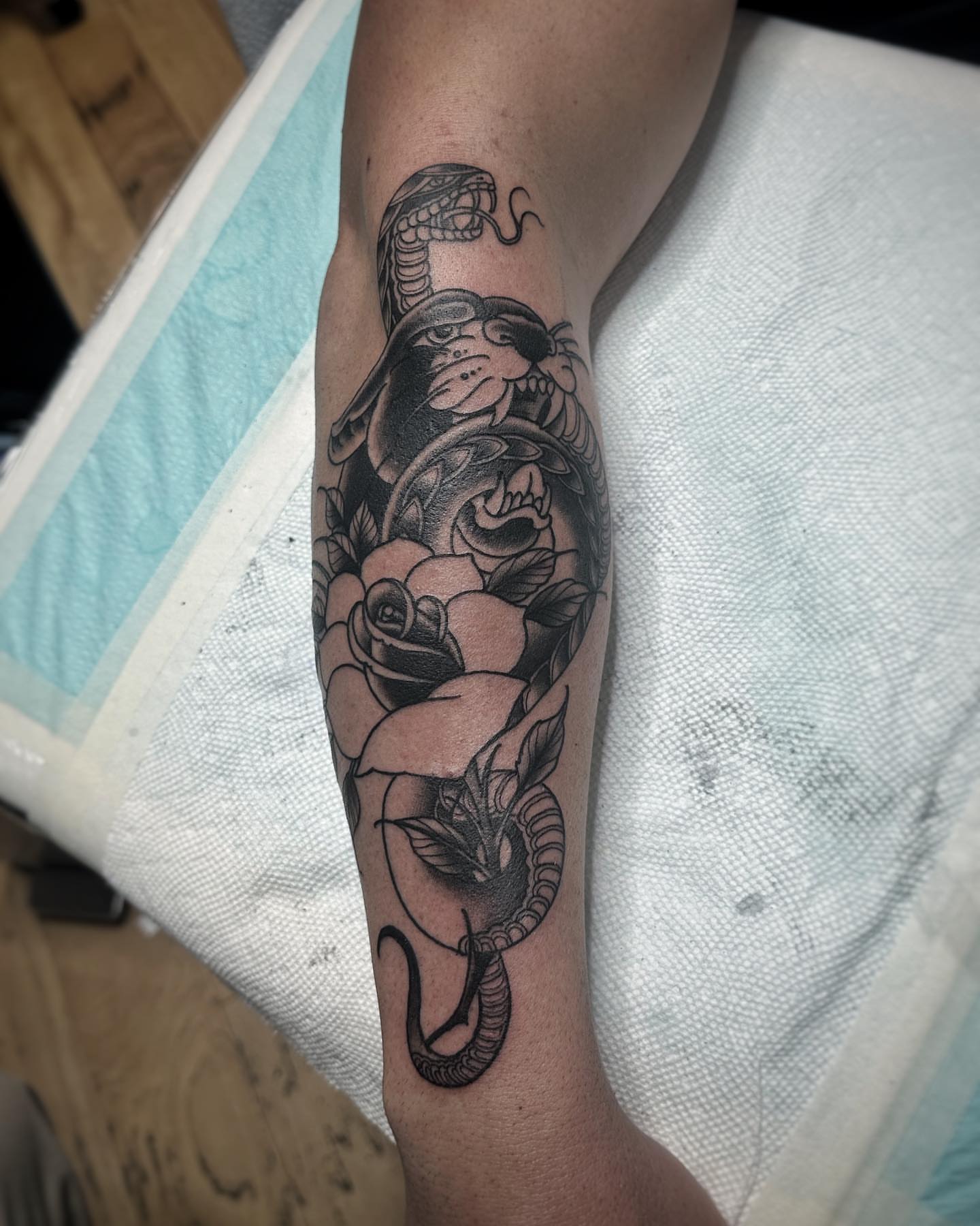 Snake and roses American traditional tattoo on the forearm by David Gray