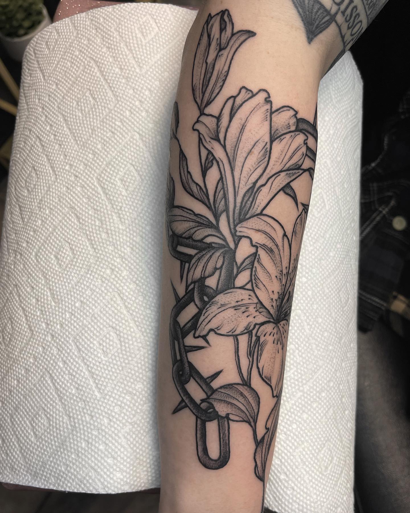 Lily and chain black and grey tattoo on the forearm by 𝐀𝐘𝐀𝐍𝐀𝐇