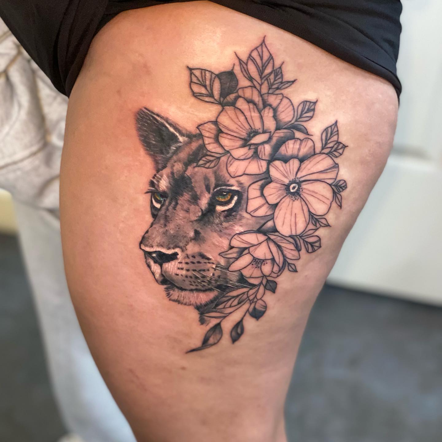 Mountain lion with flowers realism tattoo on the thigh by Zach Ashton