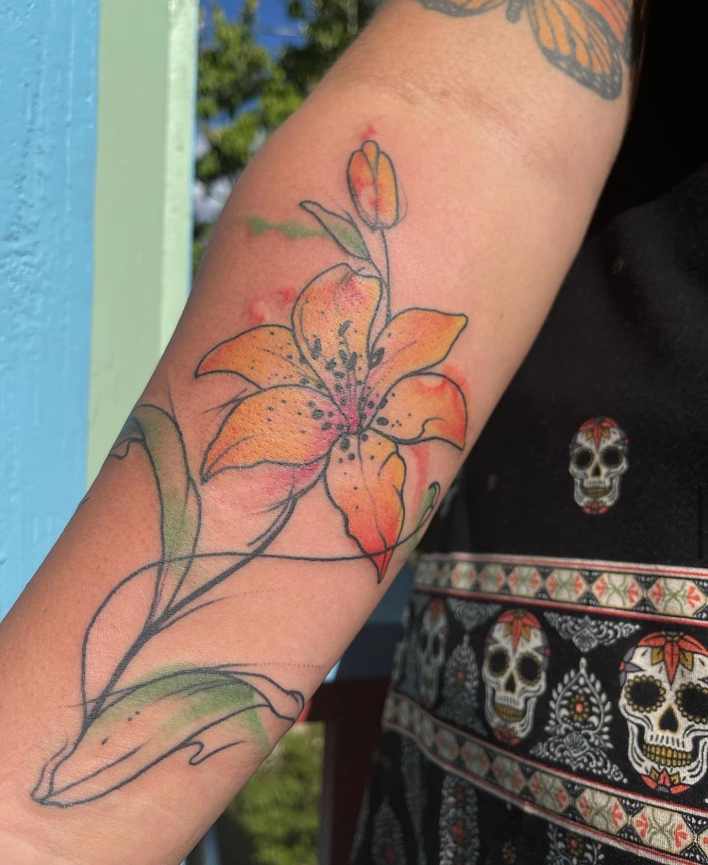 Lily watercolor tattoo on the forearm by Shamanic Ink