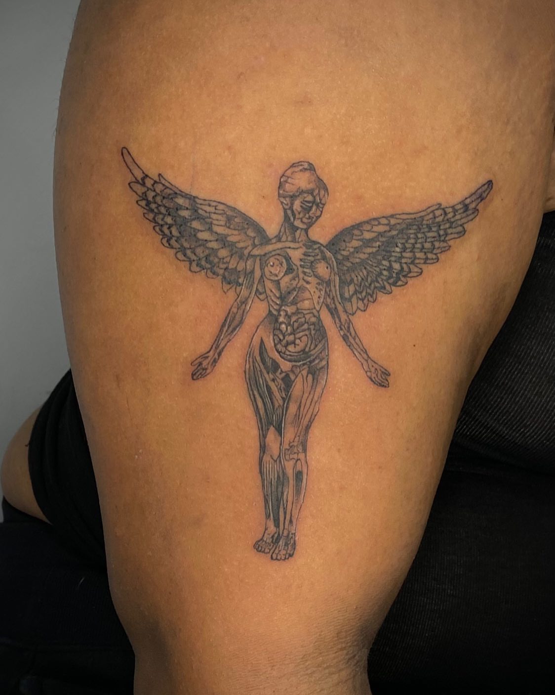 Winged anatomical figure black and grey tattoo on the thigh by Erika Nambo