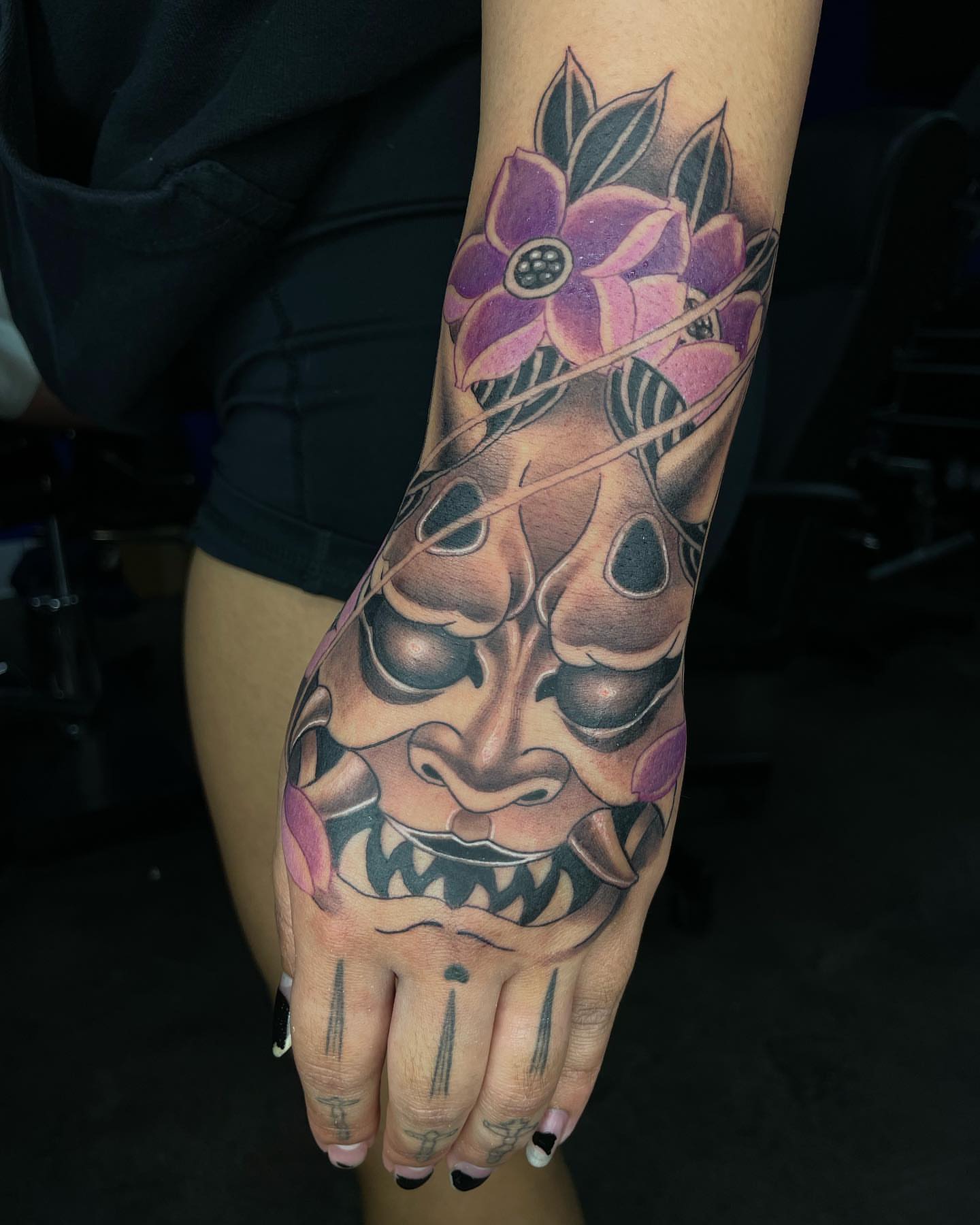 Mask with flowers American traditional tattoo on the forearm by Tam Nguyen
