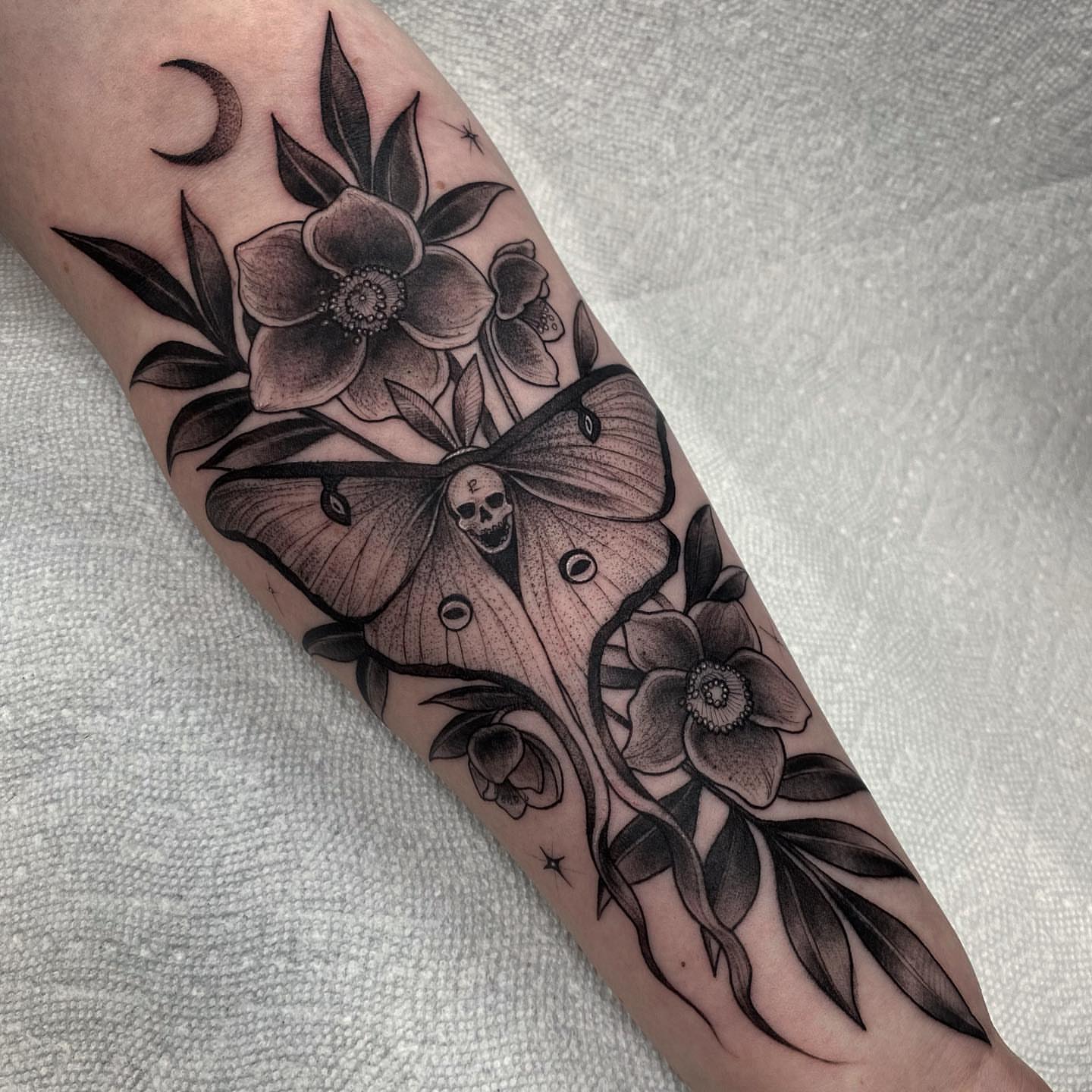 Moth and flowers realism tattoo on the forearm by Marissa Tattoos