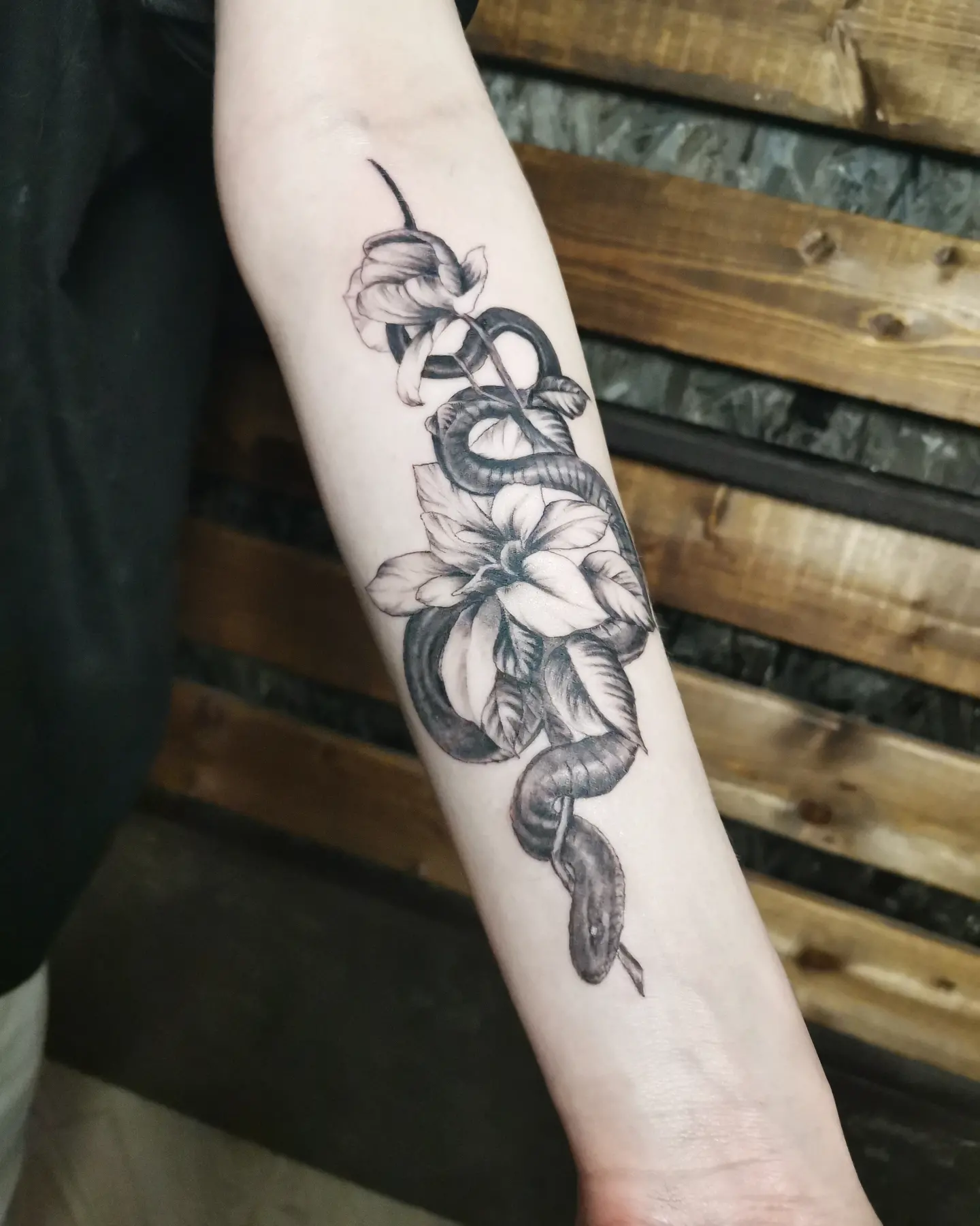 Snake and flowers realism tattoo on the forearm by Ivan Grinevich