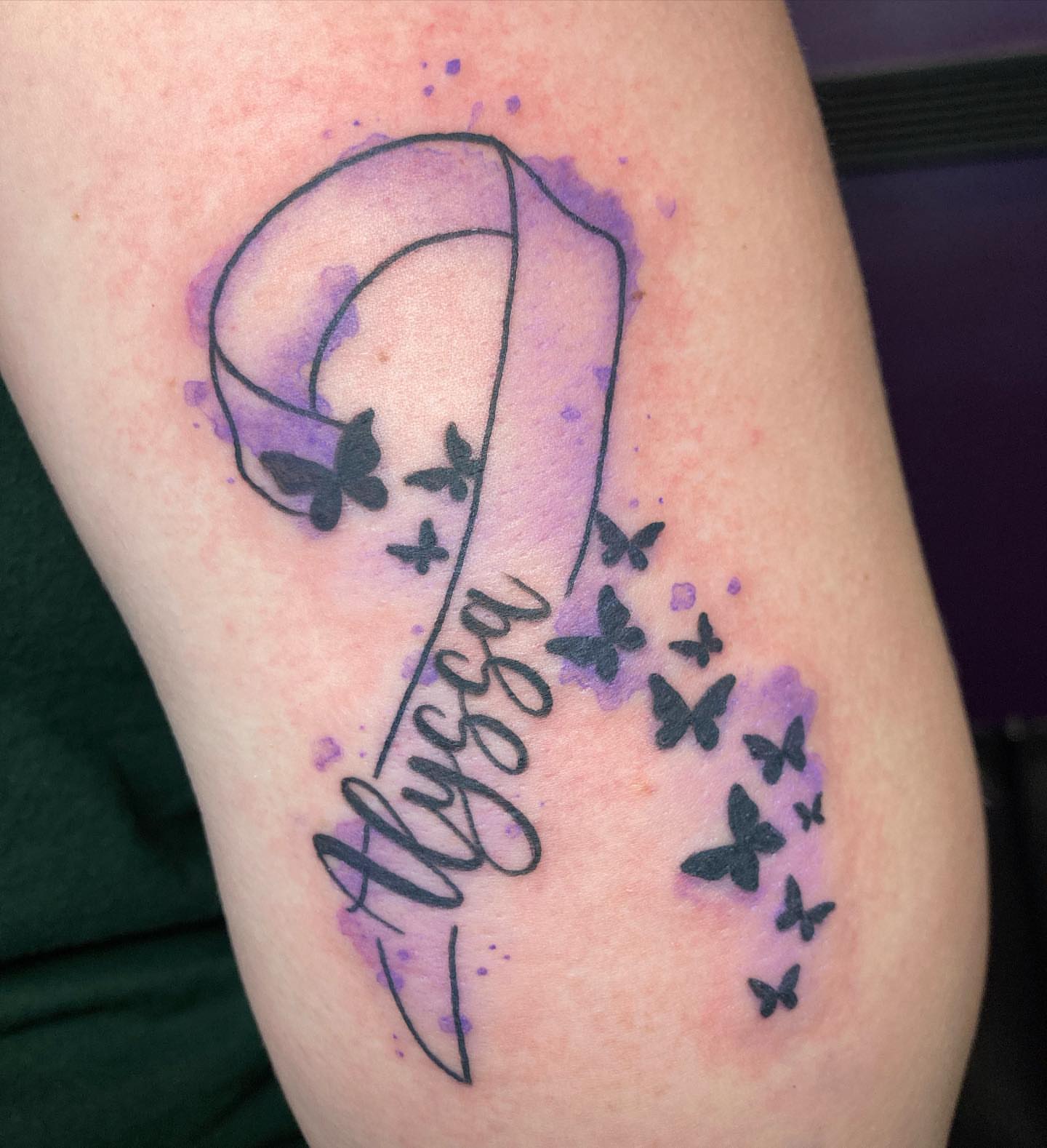Purple ribbon with butterflies watercolor tattoo on the forearm by Hali Larkin