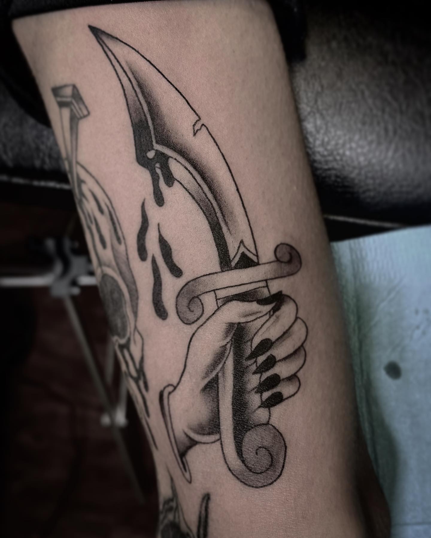 Knife and hand black and grey tattoo on the forearm by Rachel Martinez