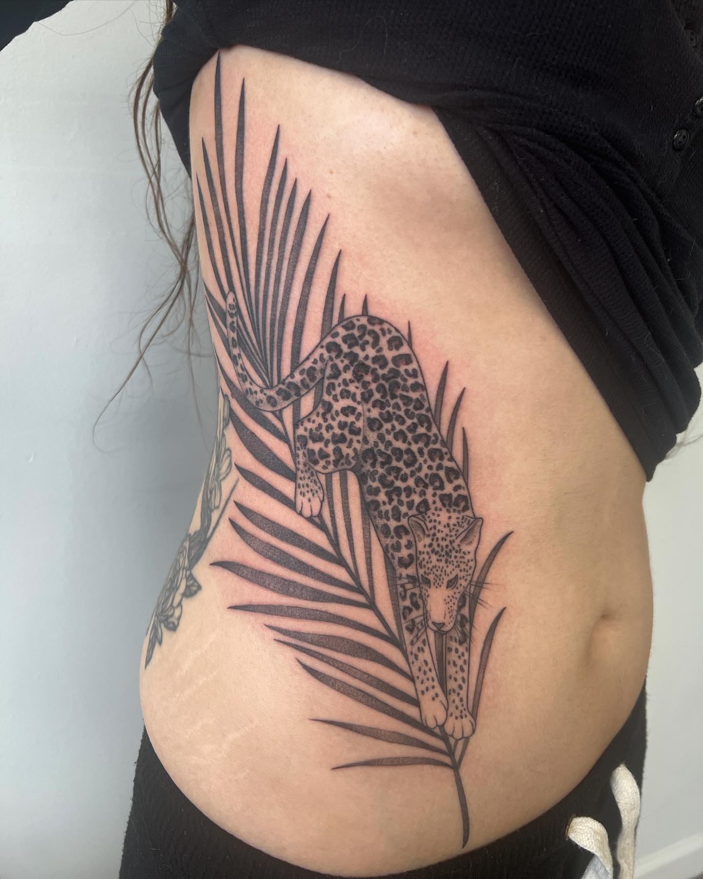 Leopard and palm leaf black and grey tattoo on the ribs by See See : botanical tattoo artist :